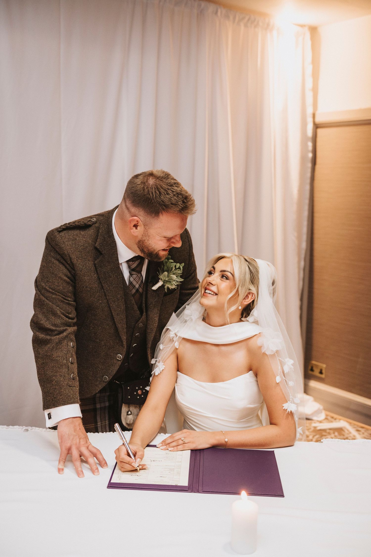 A couple shares a joyful moment while signing their marriage license during their wedding ceremony.