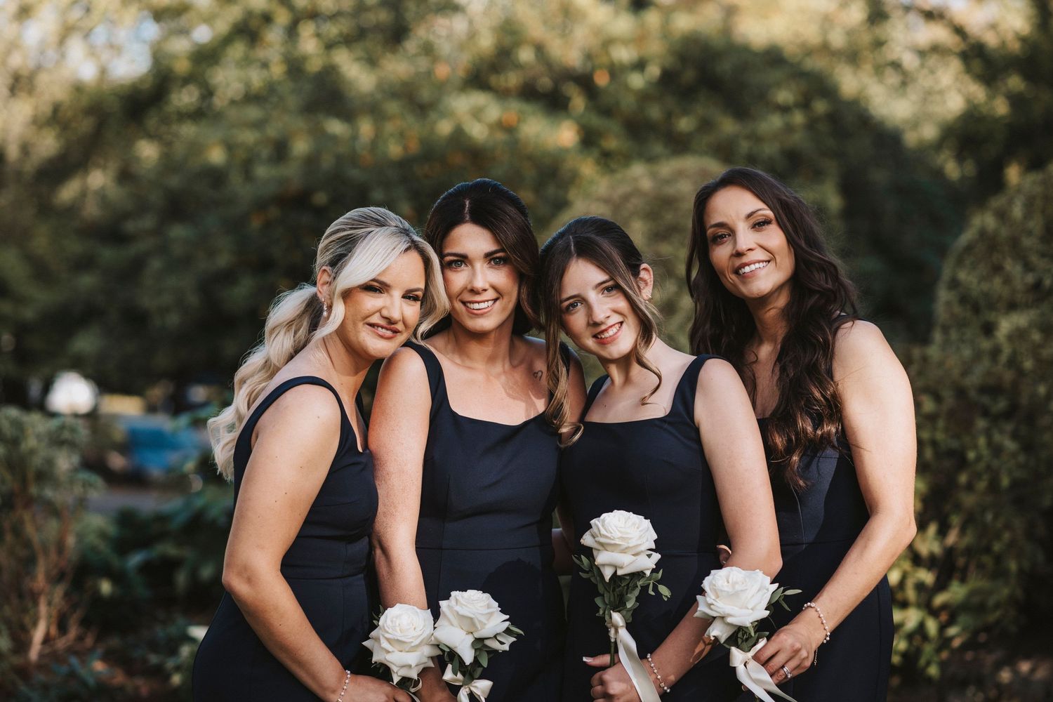 A group of bridesmaids in black dresses share a candid laughing moment together during a wedding photo session.