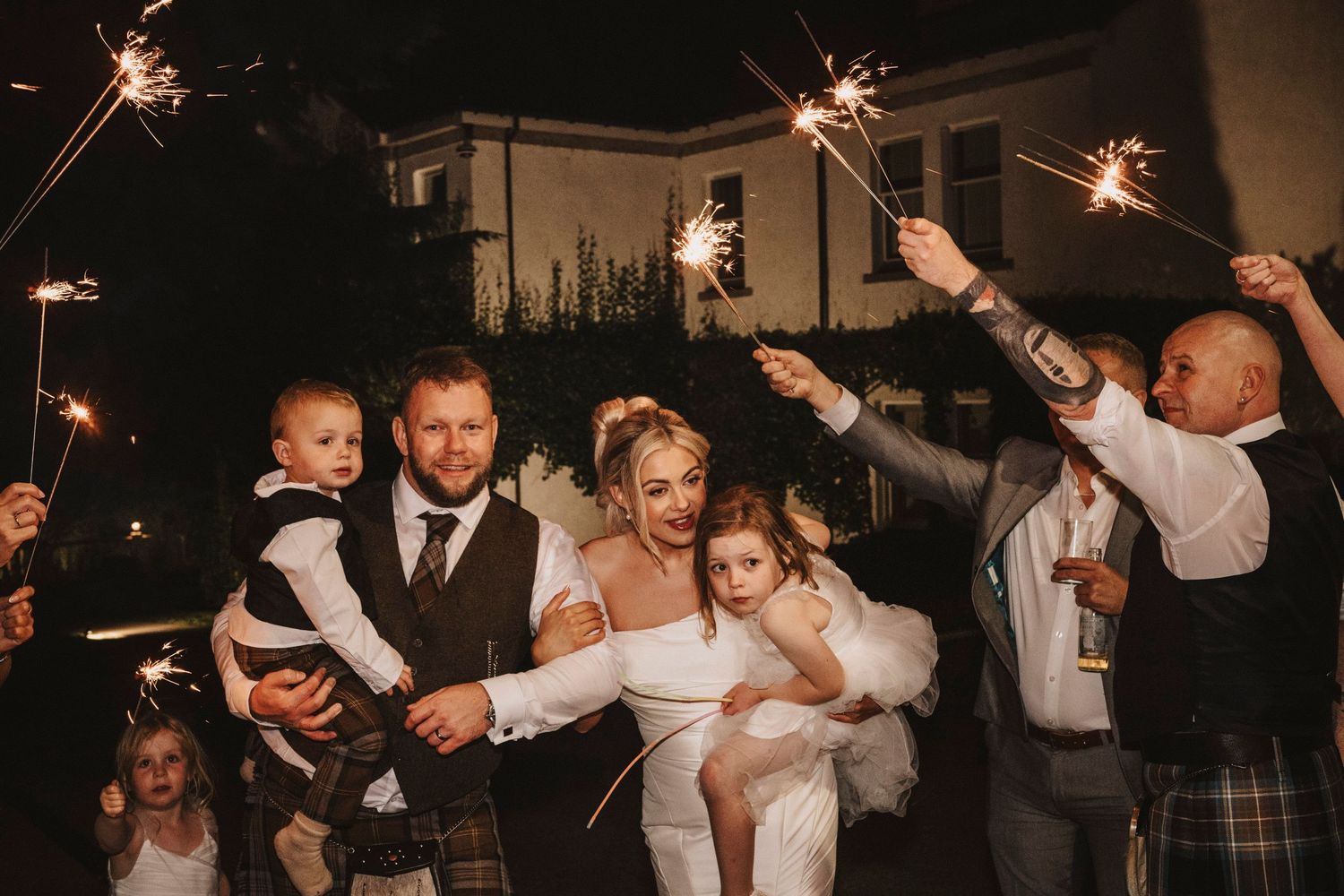 Wedding guests dance and celebrate with sparklers creating a magical nighttime atmosphere at a reception celebration.