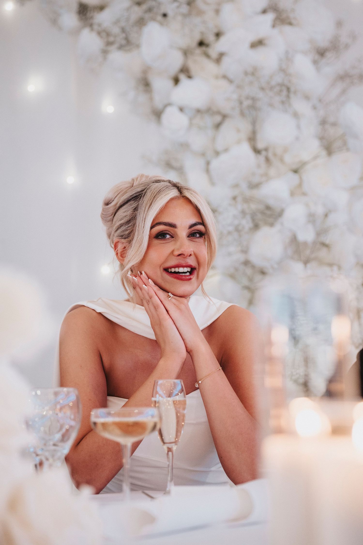 A dreamy bridal photoshoot with white floral decor and soft candlelight creating a romantic atmosphere.