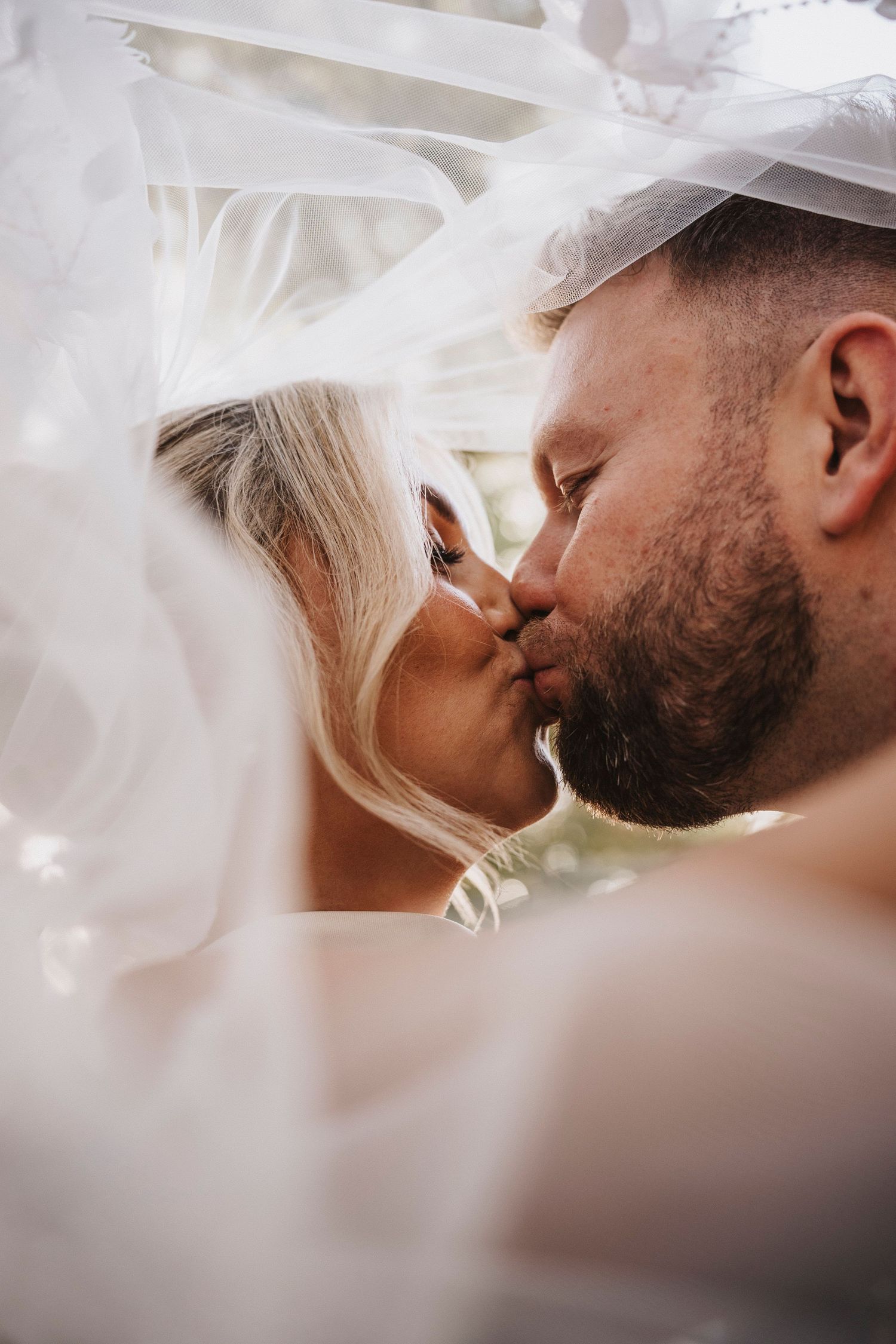 A romantic wedding photo sequence showing close-up shots of a couple sharing tender kisses under a flowing veil.