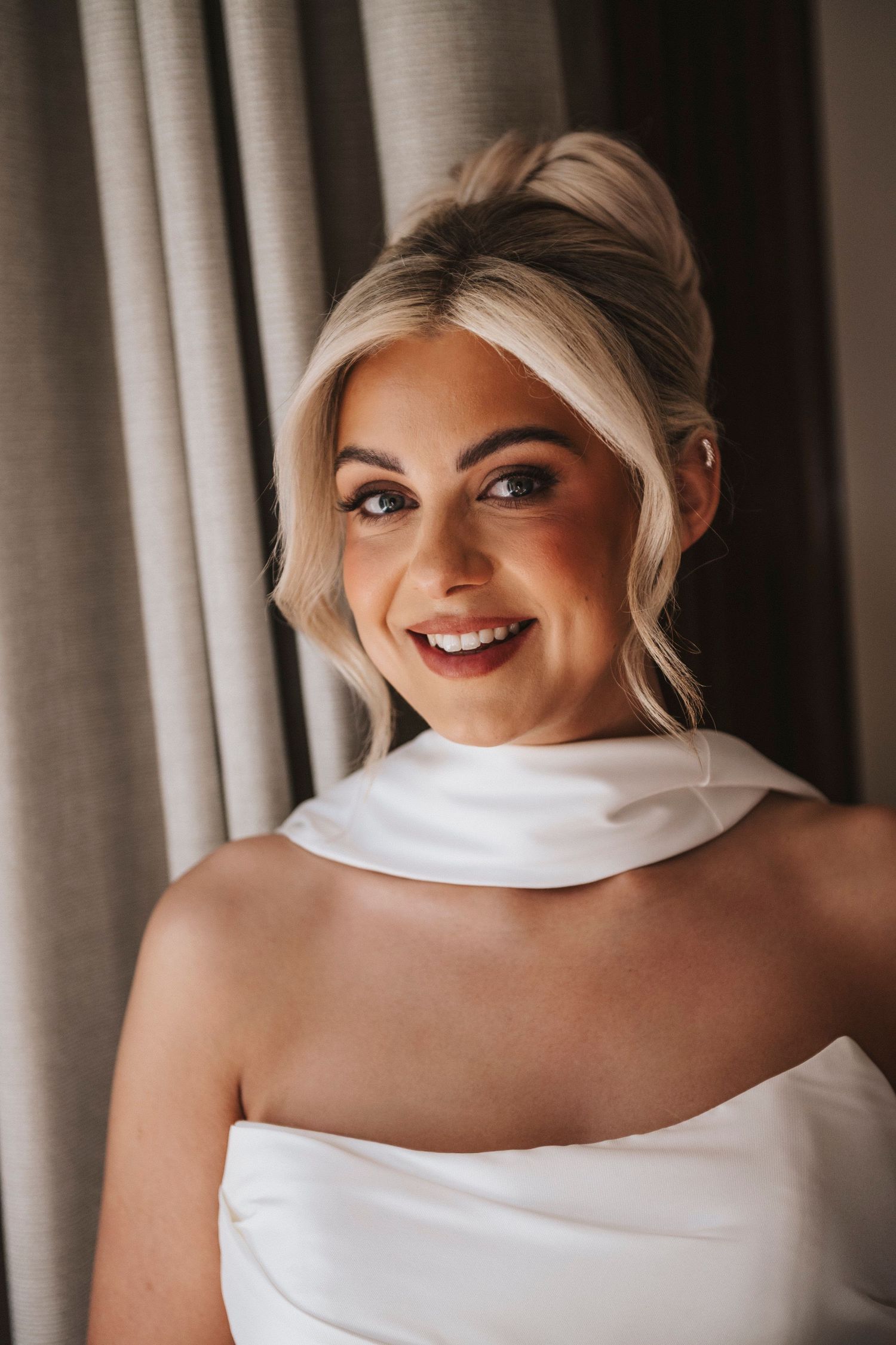 Closeup portrait series of someone wearing a white off-shoulder dress against a curtained background.