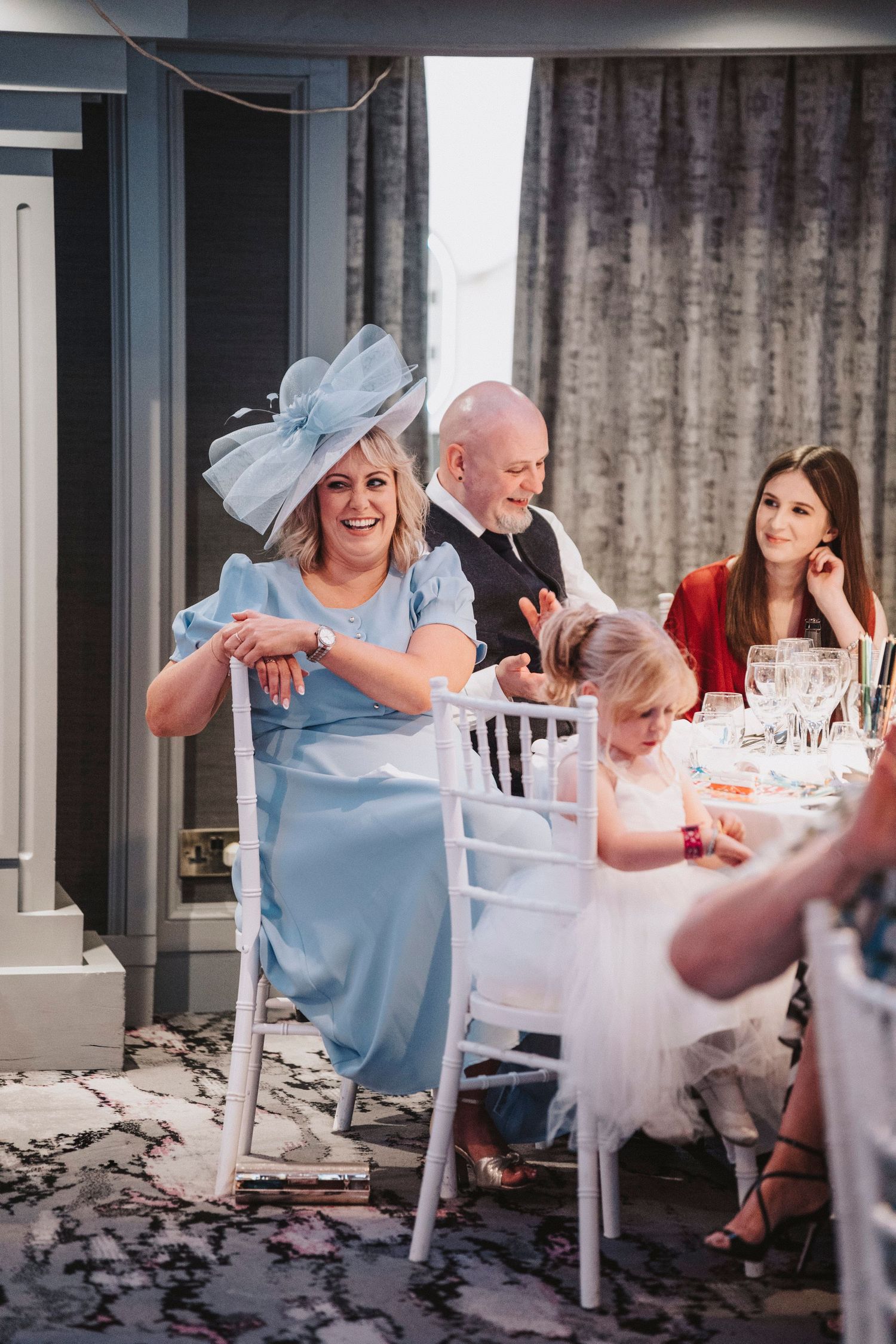 Wedding guests enjoying a reception at a table with elegant decor and confetti scattered on the floor.
