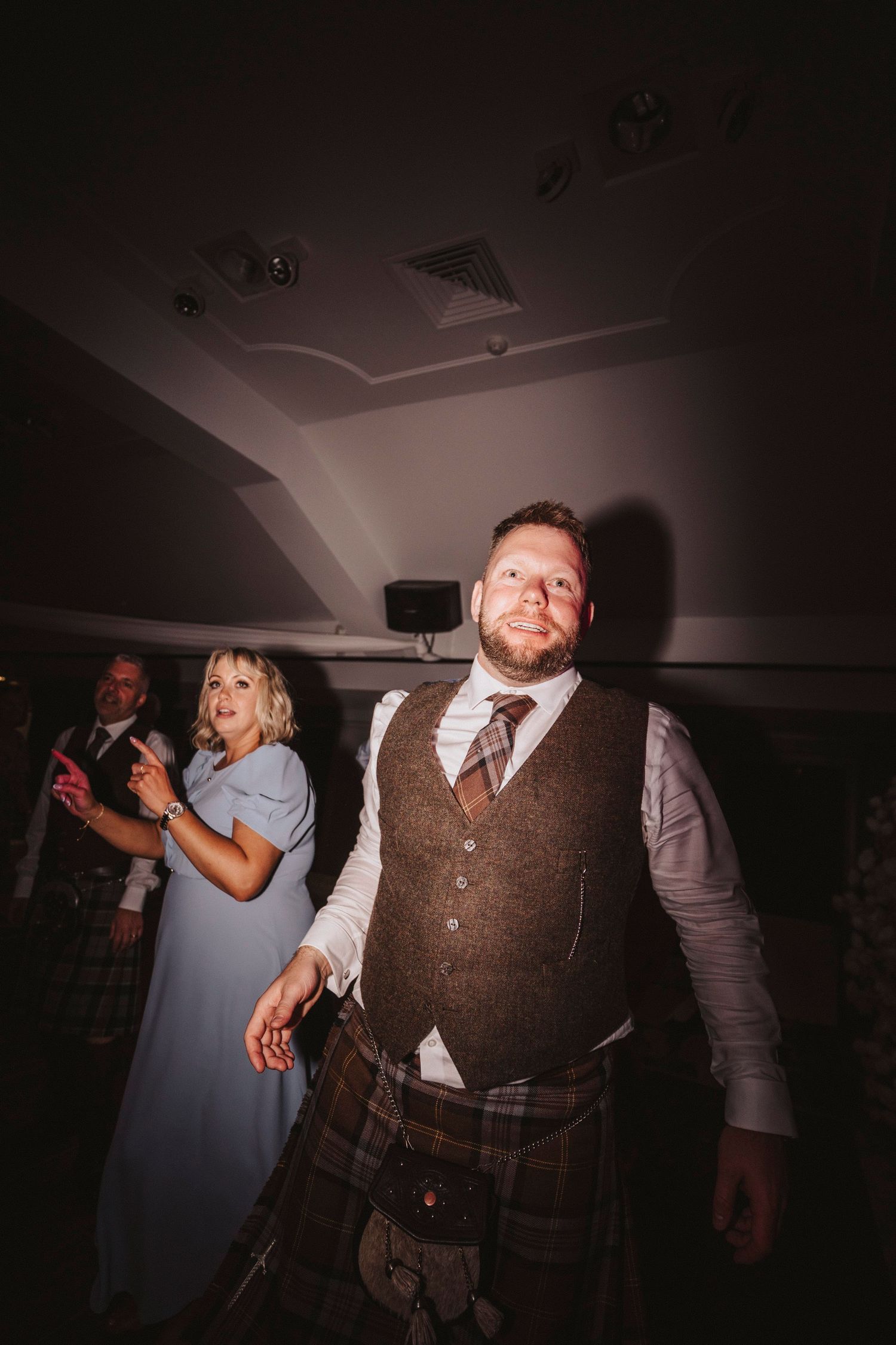 Dark and moody dance floor photos showing wedding guests dancing and celebrating at a reception.