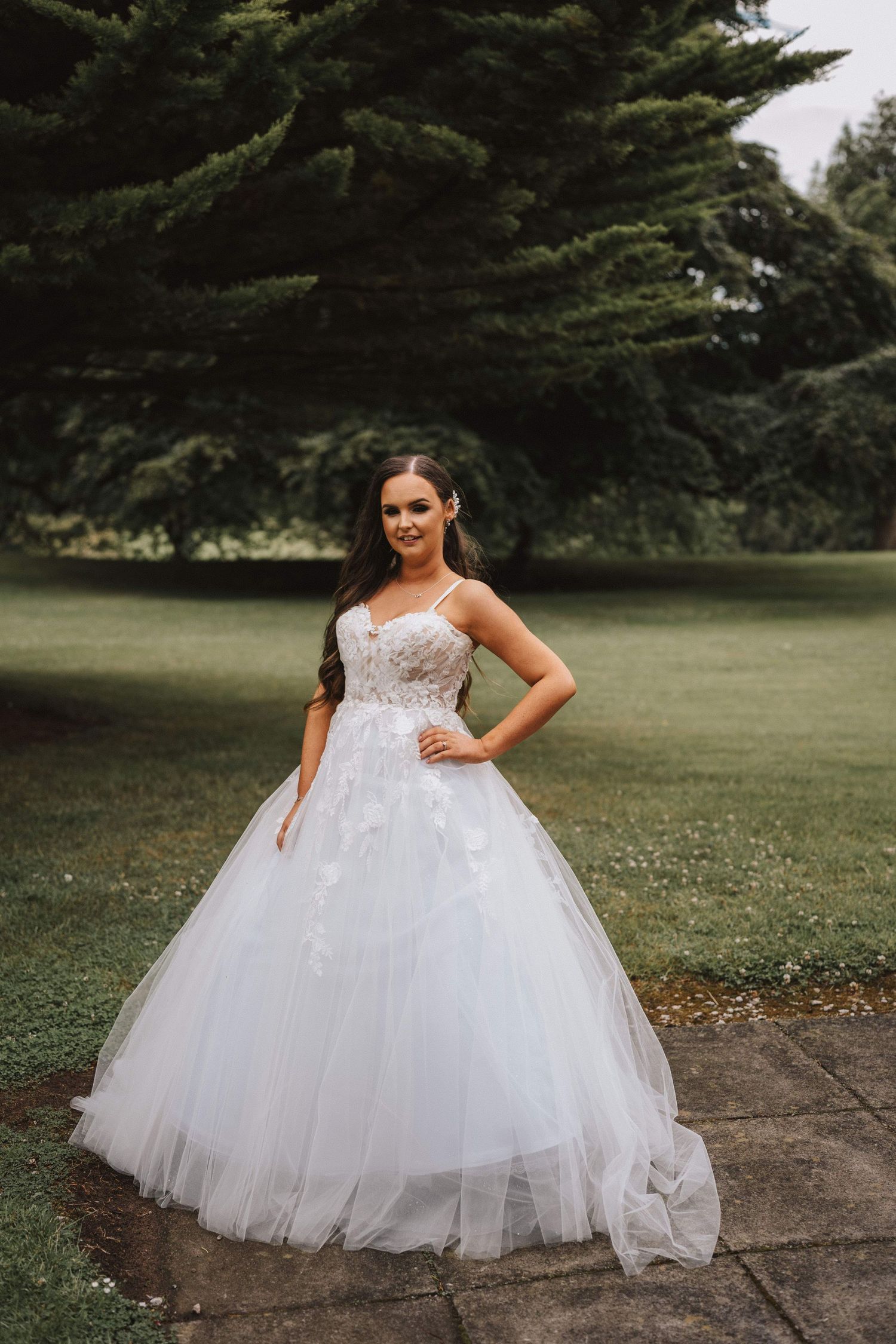 A stunning white tulle wedding gown with a lace bodice photographed in a garden setting.
