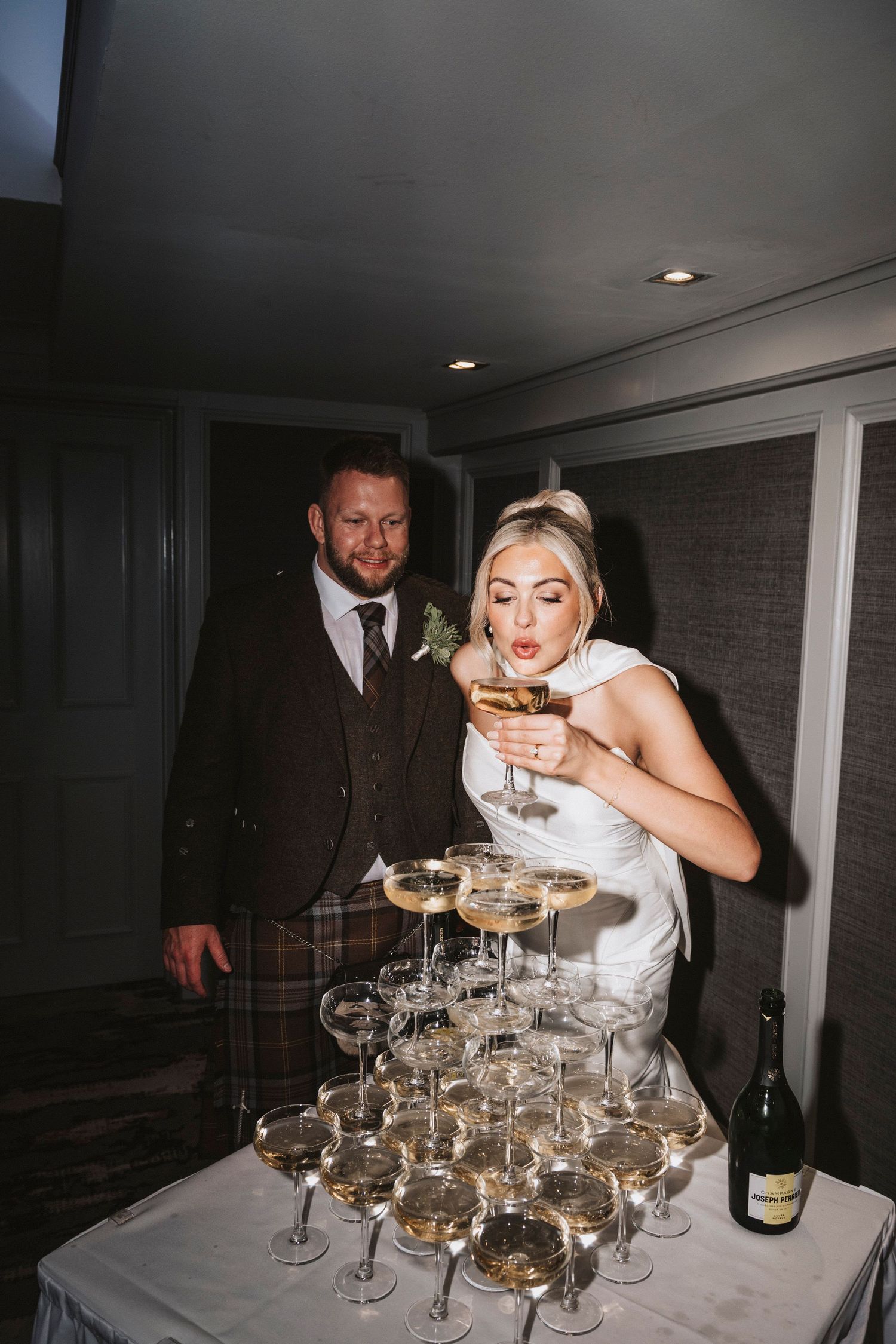 A champagne tower being carefully stacked with coupe glasses at an elegant evening event.