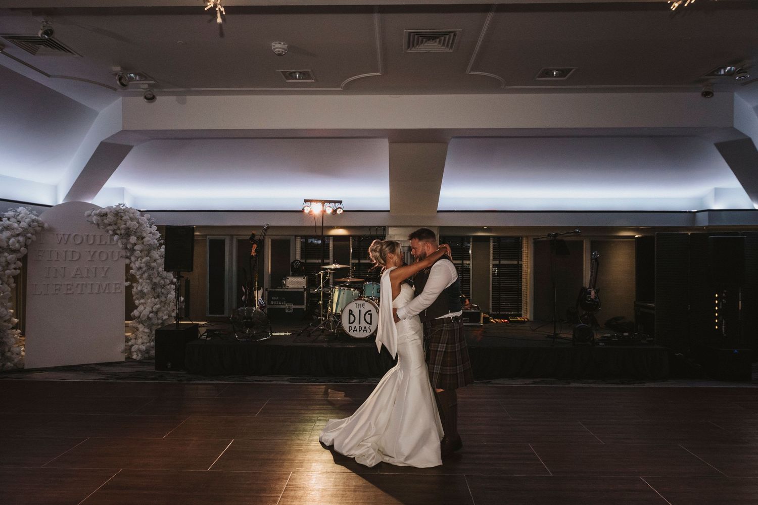 Wedding reception dance floor with guests celebrating in a dimly lit ballroom venue.