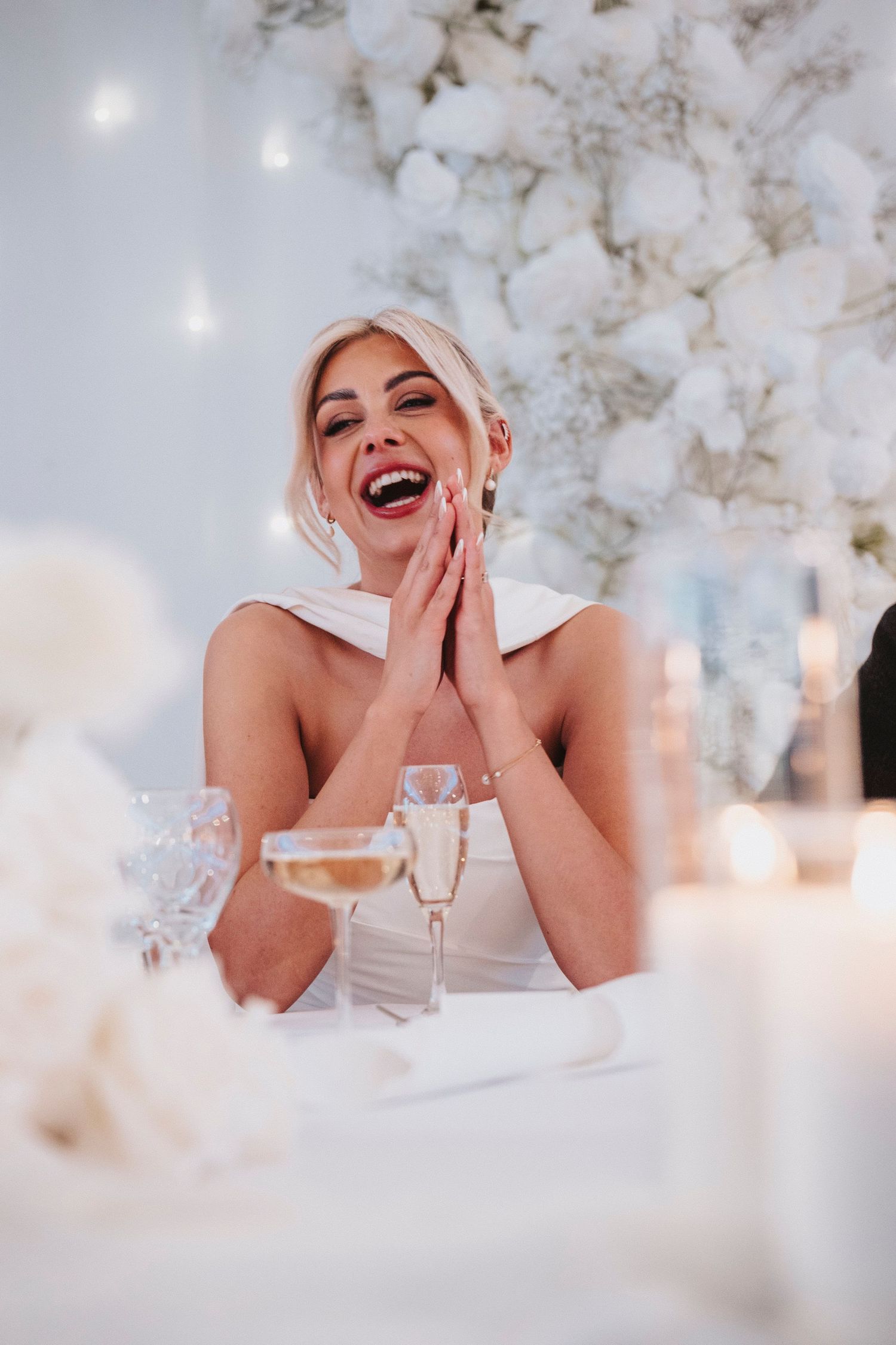 A series of joyful candid moments captured against a dreamy white floral backdrop at an elegant table setting.
