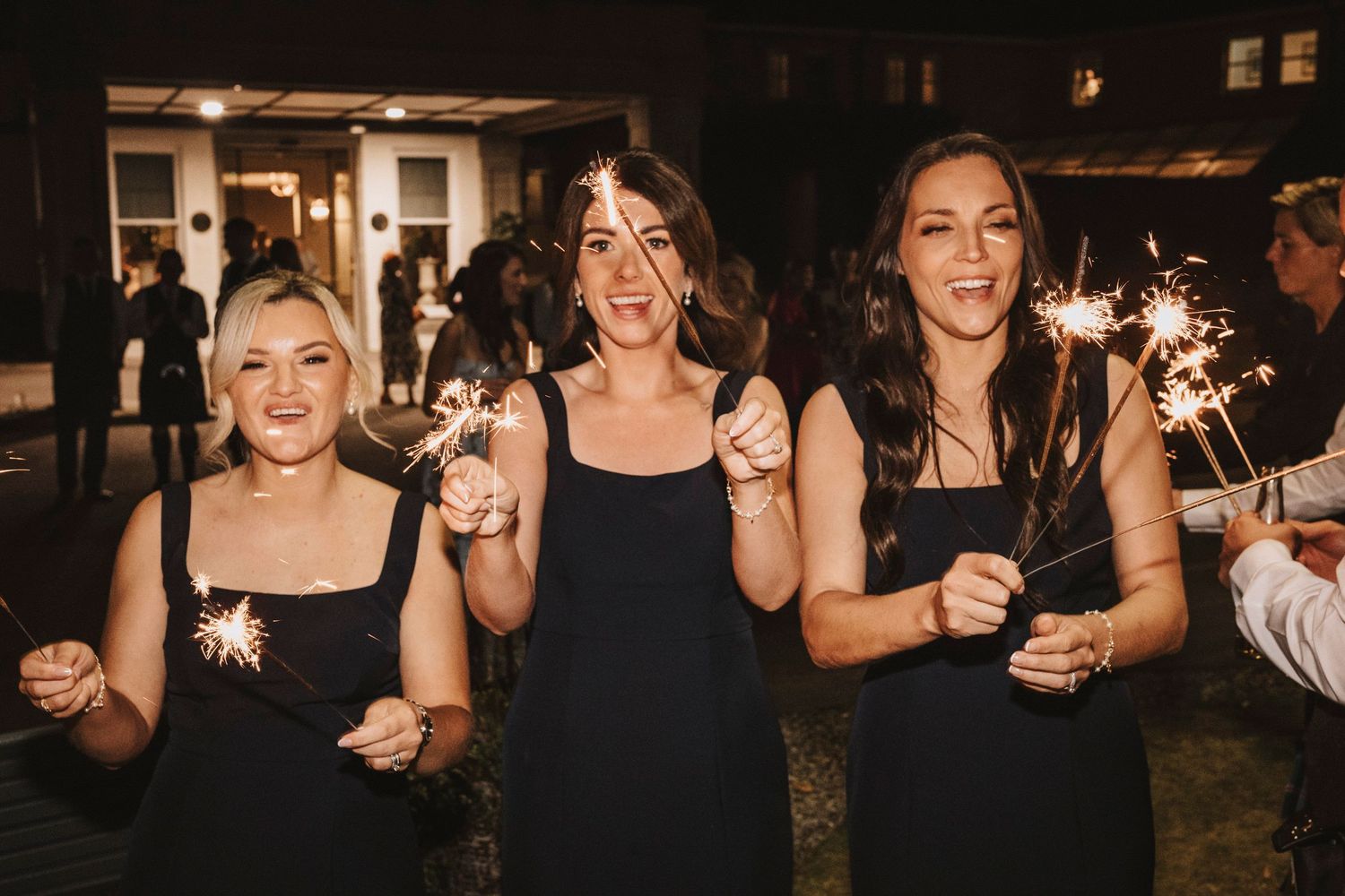 Group of people holding sparklers at a nighttime celebration, creating a festive outdoor atmosphere.