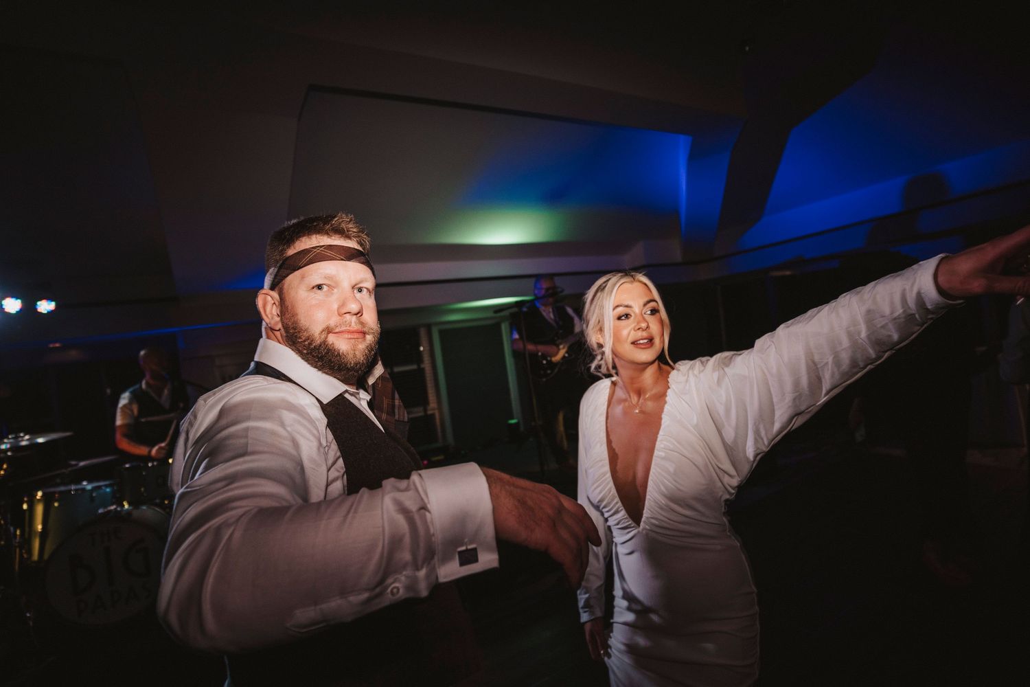 Two people dancing and having fun together at a nighttime event with blue lighting in the background.