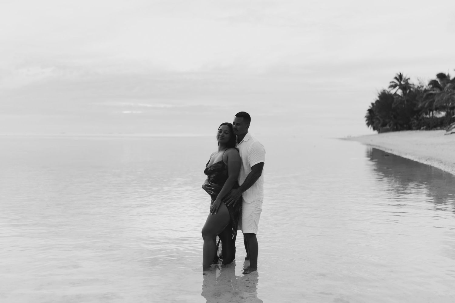 Couple walking along the water’s edge in the lagoon – romantic Rarotonga engagement shoot