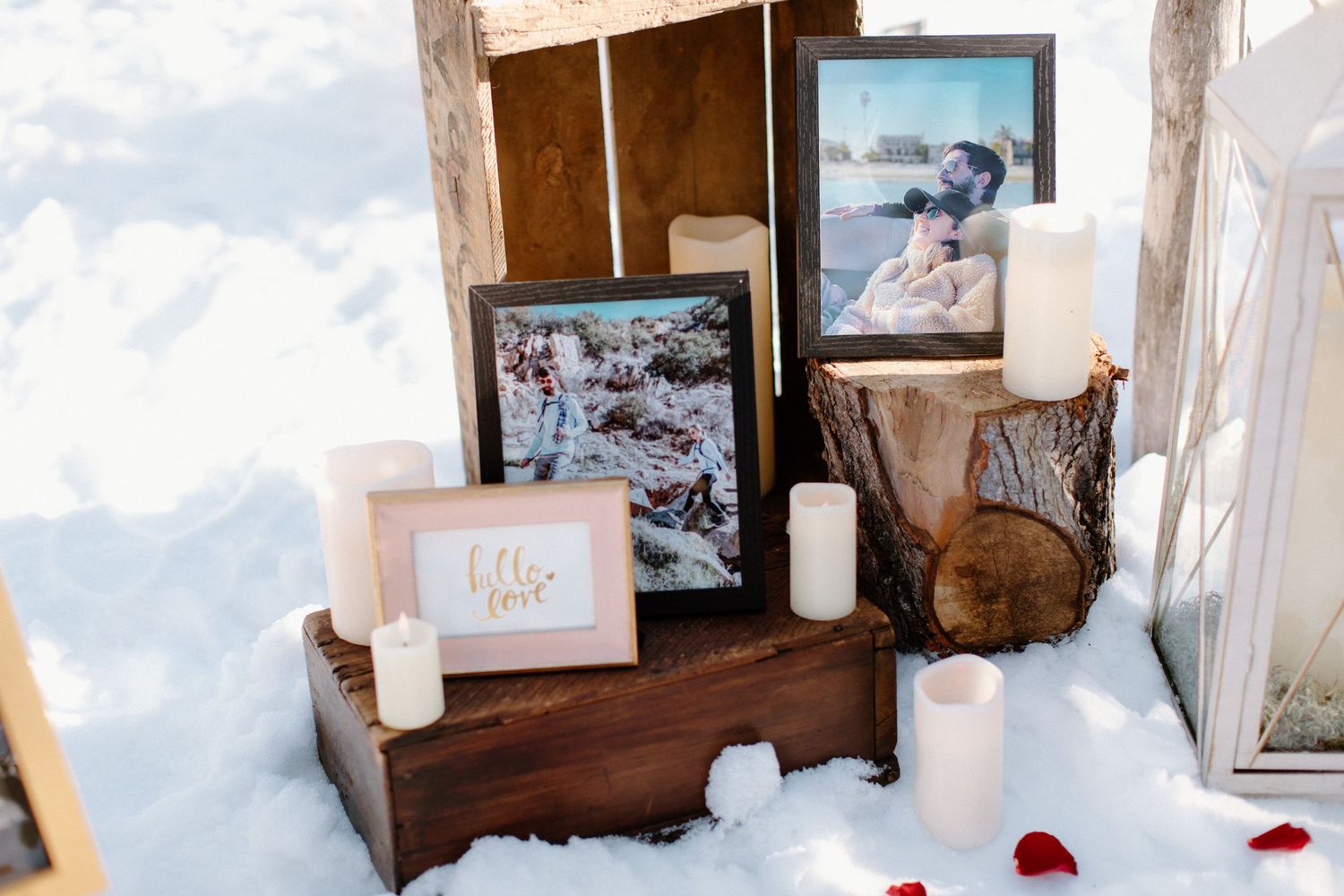 Rustic wooden display with photos, candles and decorations set in snow.