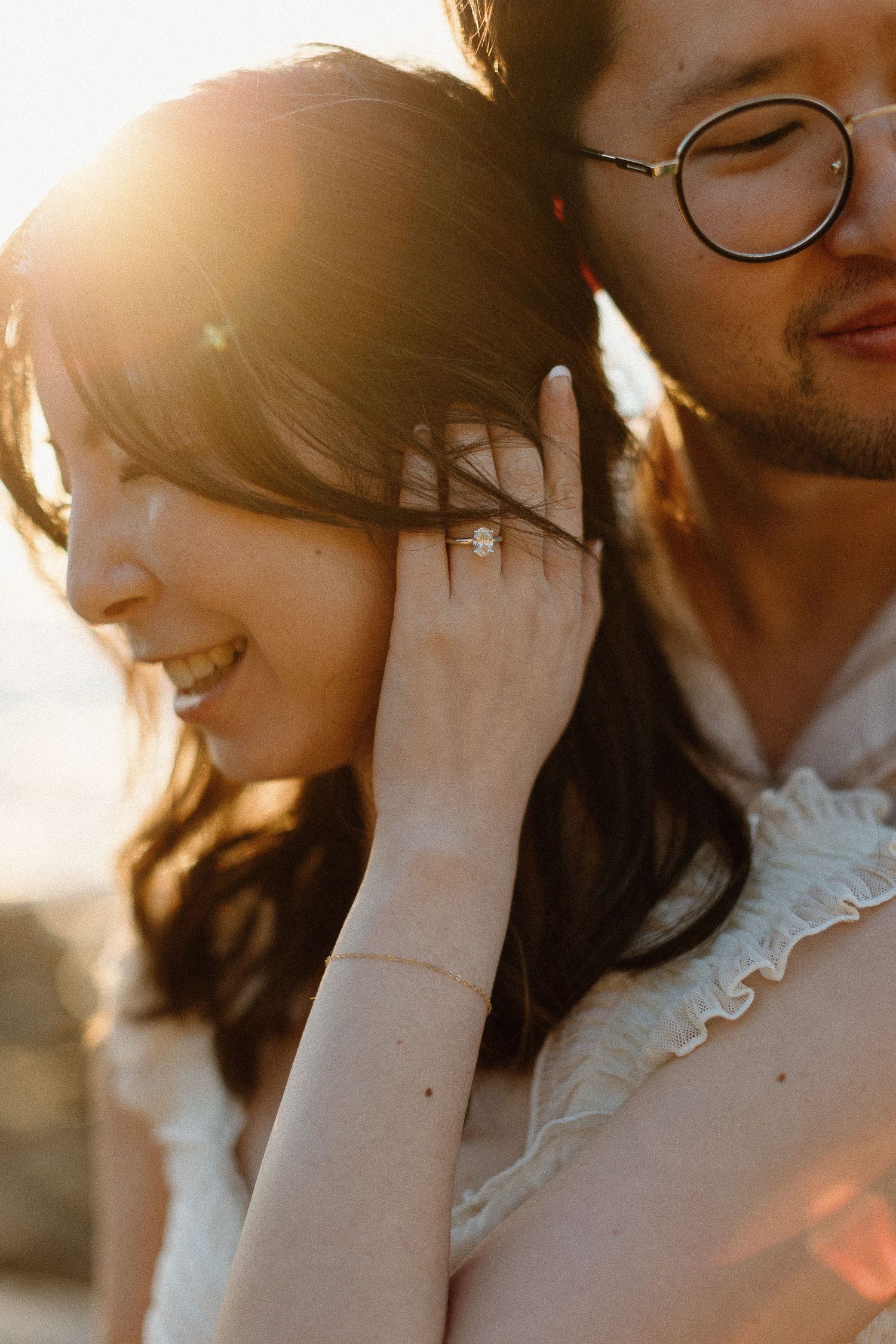 Sunlit portrait with sparkling engagement ring in golden light.