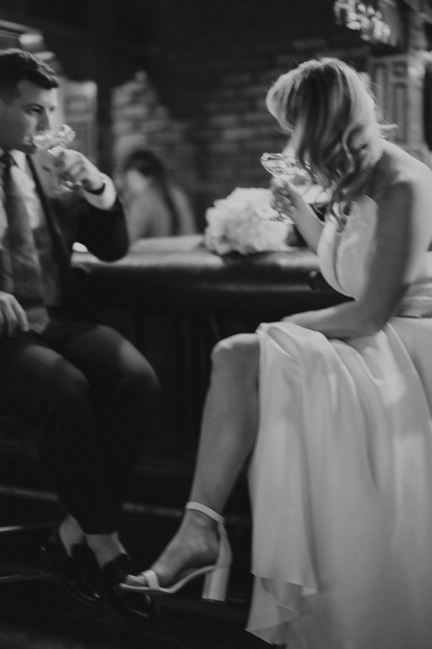 A black and white photo of a couple enjoying drinks together at their wedding reception.