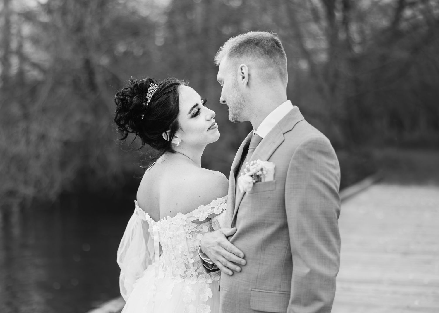 A black and white portrait of a romantic couple on their wedding day sharing an intimate moment outdoors.
