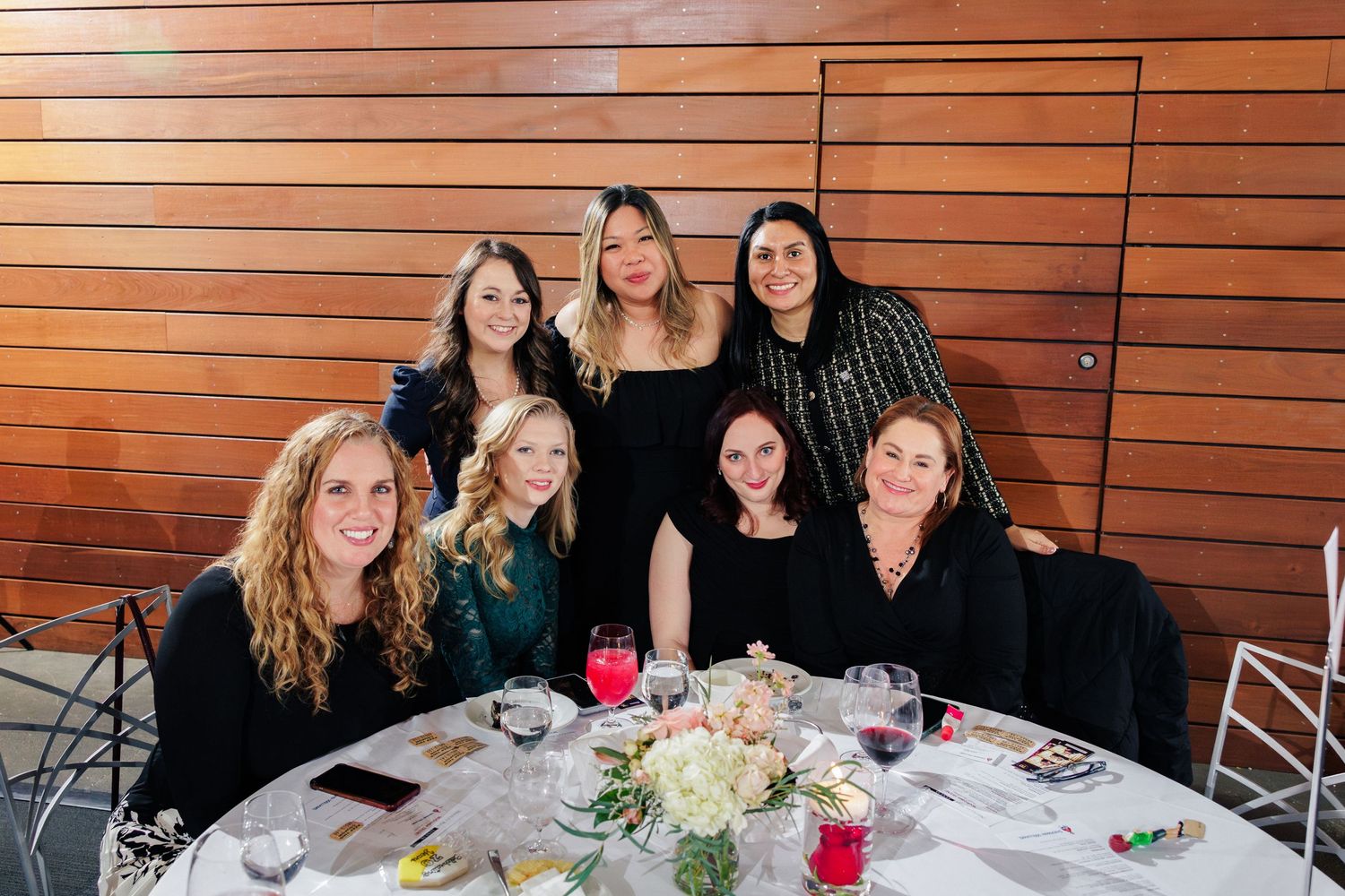 Group photo of friends gathered around a dining table at a special event.