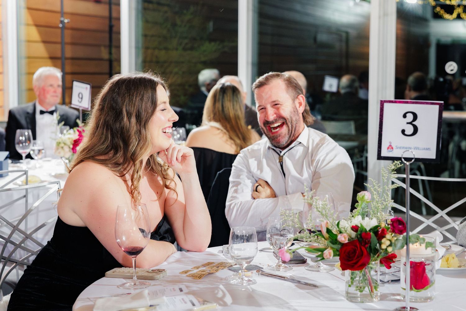 Two dinner guests sharing a lighthearted moment at an elegant table setting.