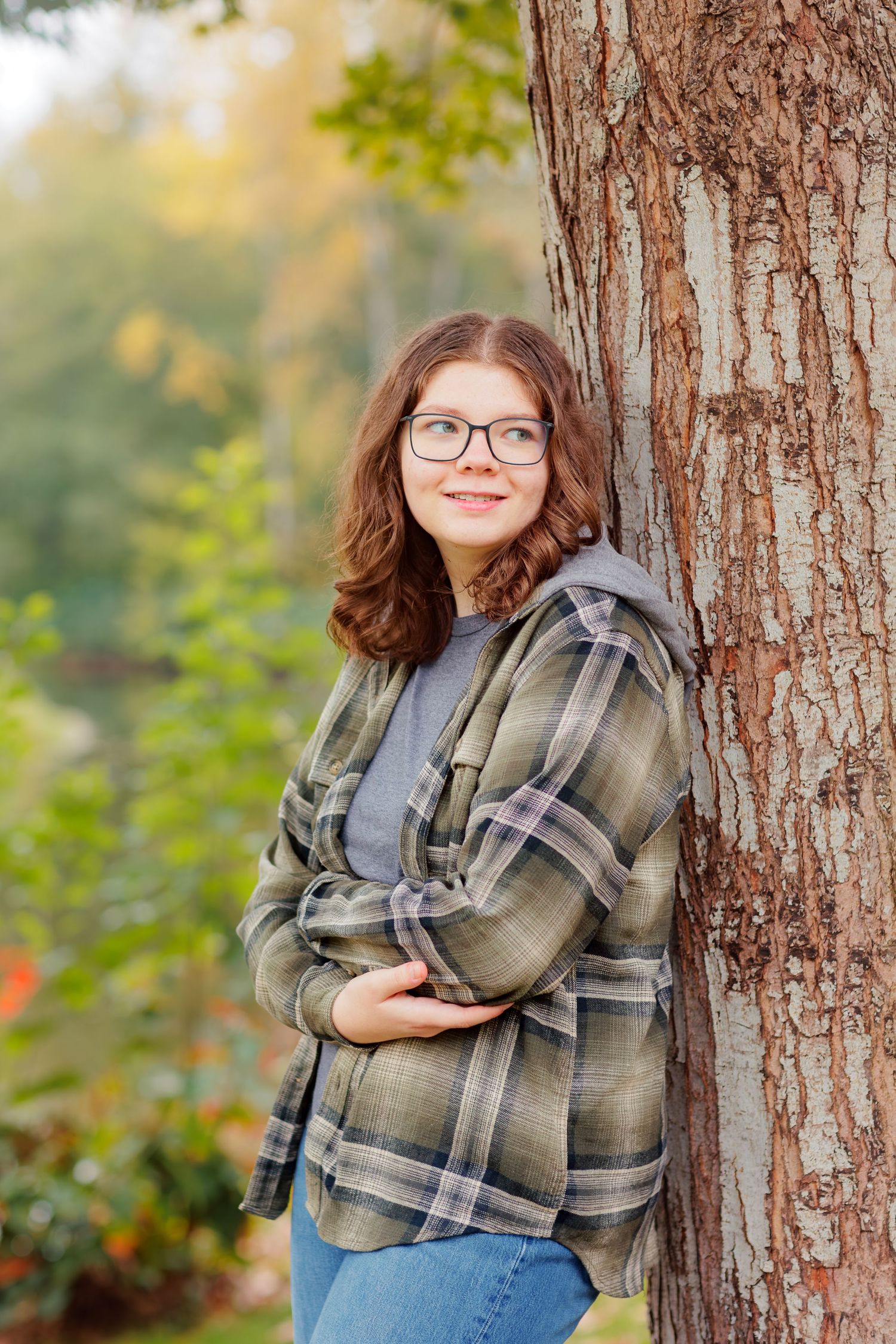 A series of four outdoor portrait photos against a tree trunk showing someone wearing glasses and a plaid shirt.