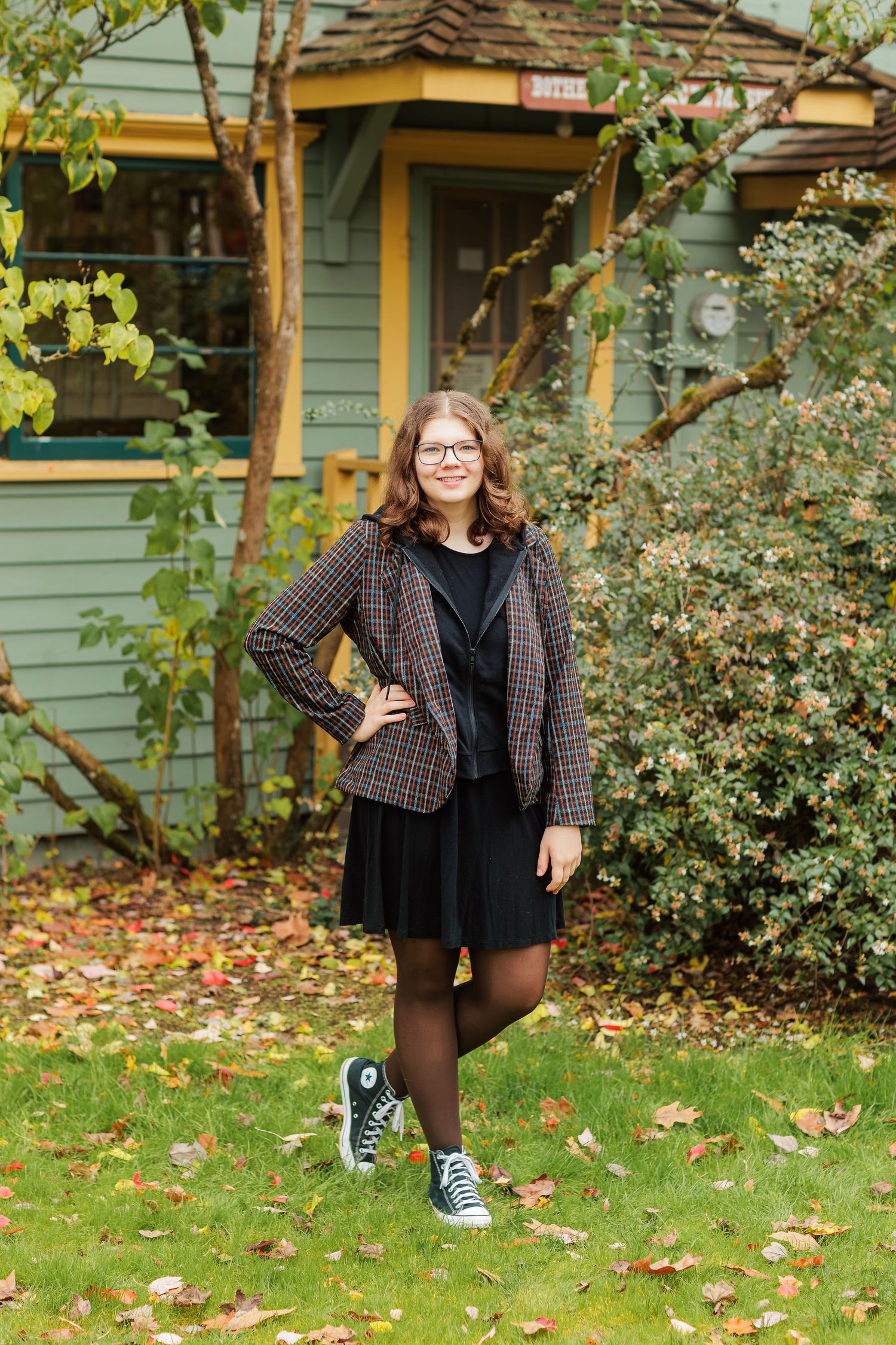 A teen girl posing with her hand on her hip in front of a rustic historic building.