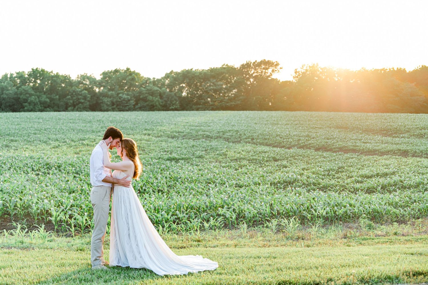 Newlyweds embrace in green field during golden hour wedding photo session by Stephanie Coulter Photography