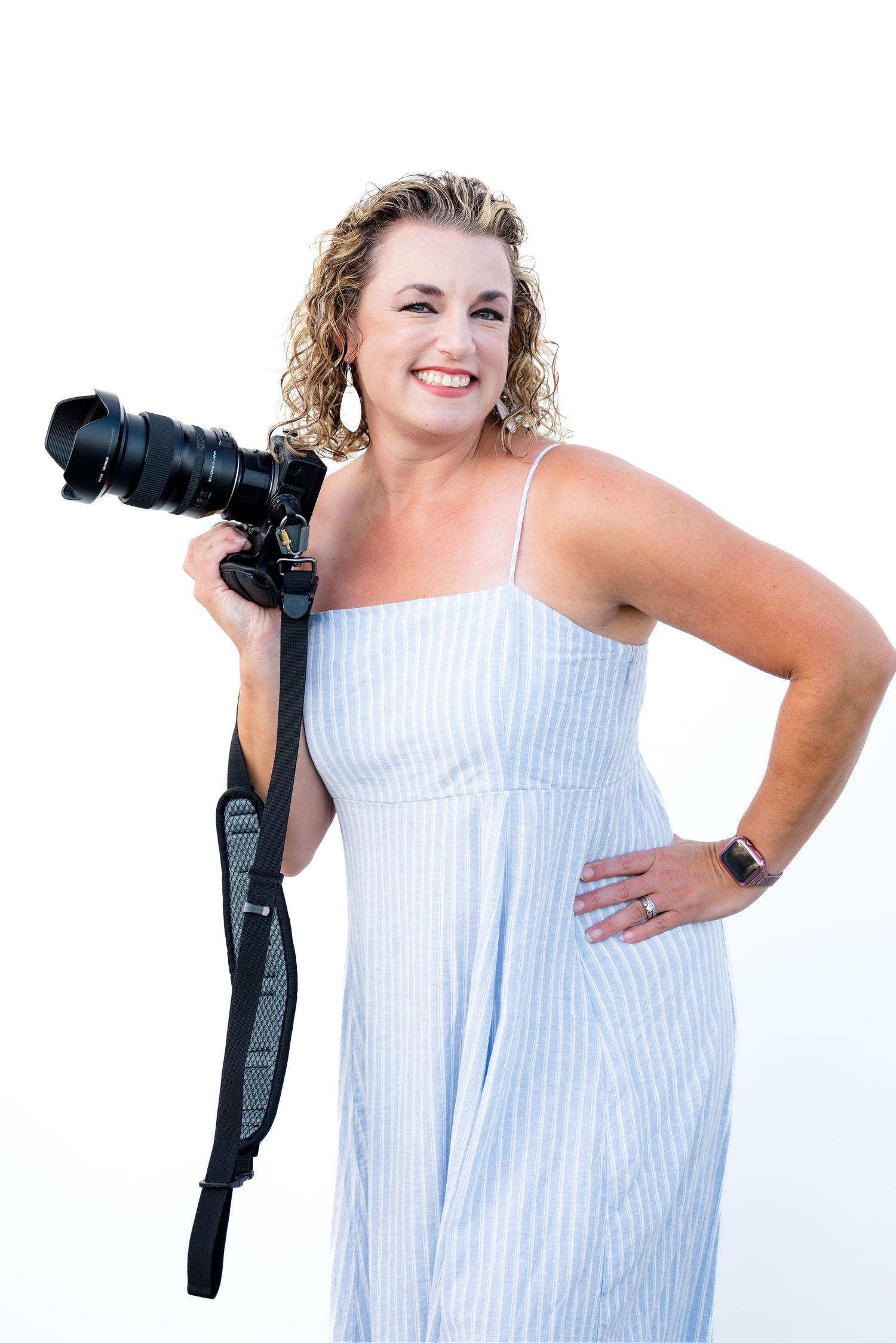 Stephanie Coulter Photographer in striped summer dress poses confidently with professional camera equipment