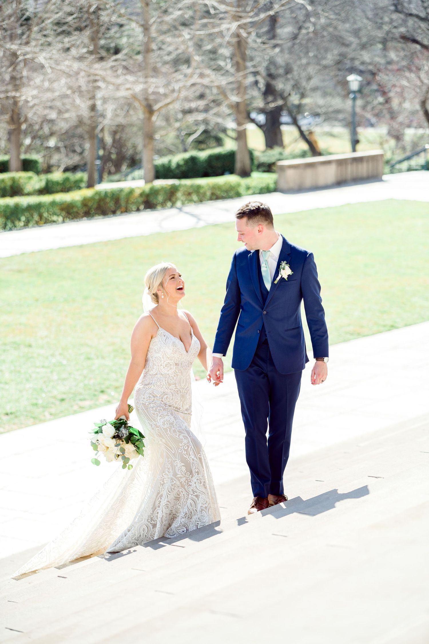 Couple walking and laughing together in formal wedding attire on snowy winter day by Stephanie Coulter Photography