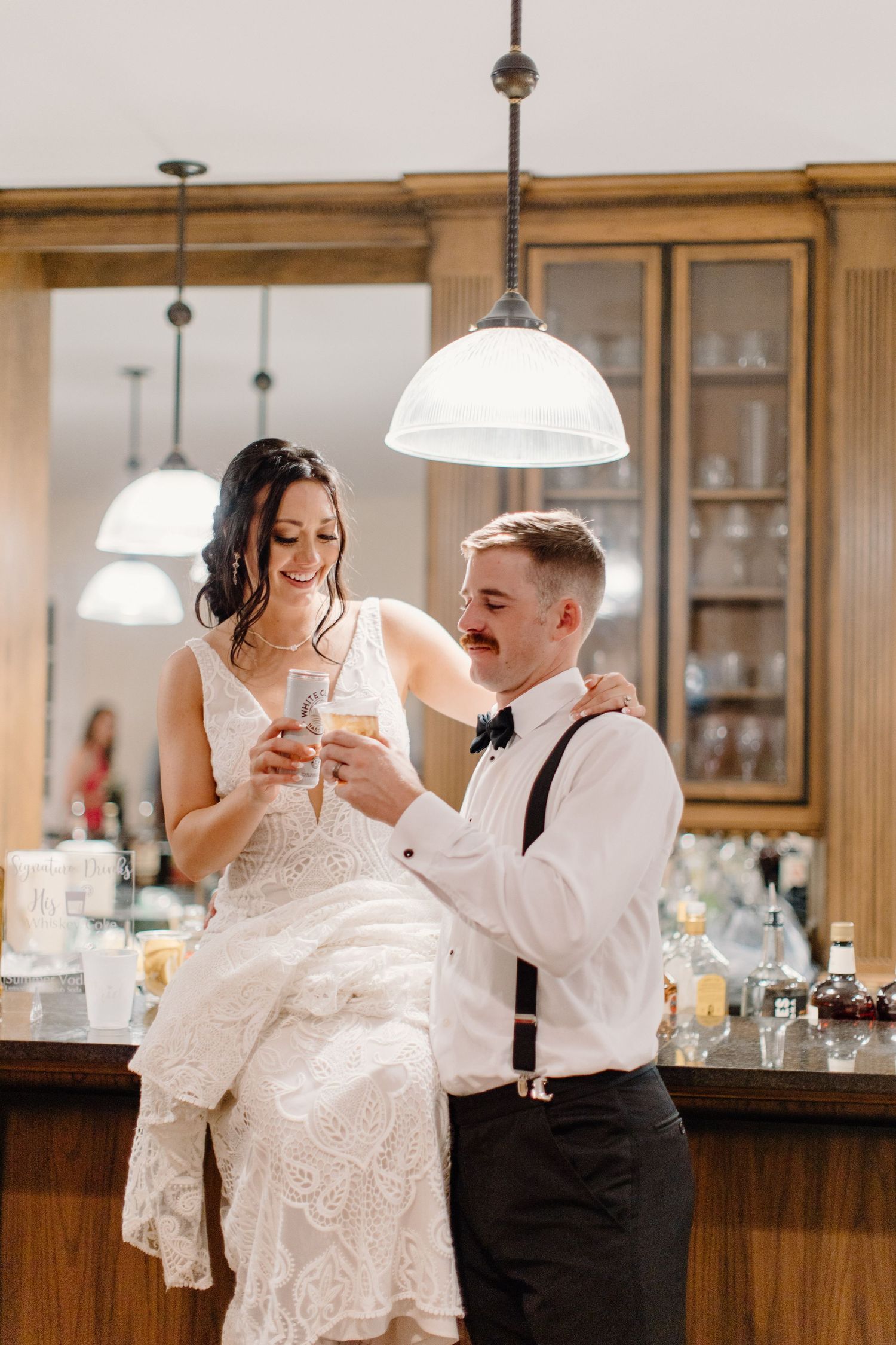 Bride and groom sharing a champagne toast at a vintage bar during their wedding reception.