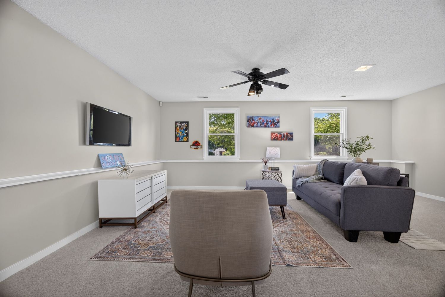 Bright living room with gray sofa, ceiling fan, and large windows.