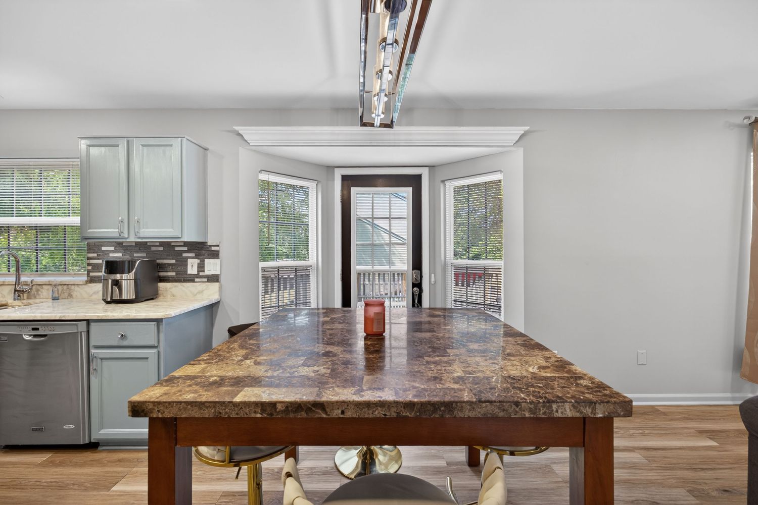 Kitchen with granite island, hardwood floors, gray cabinets, and French doors leading to a sunlit porch.