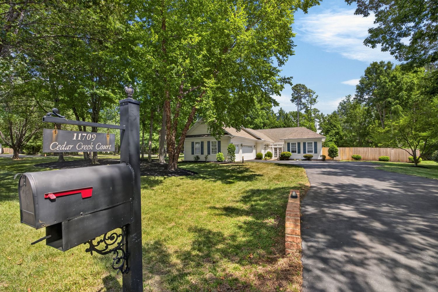 Tree-lined driveway leads to a charming suburban home at 11709 Cedar Court, surrounded by lush green lawns.