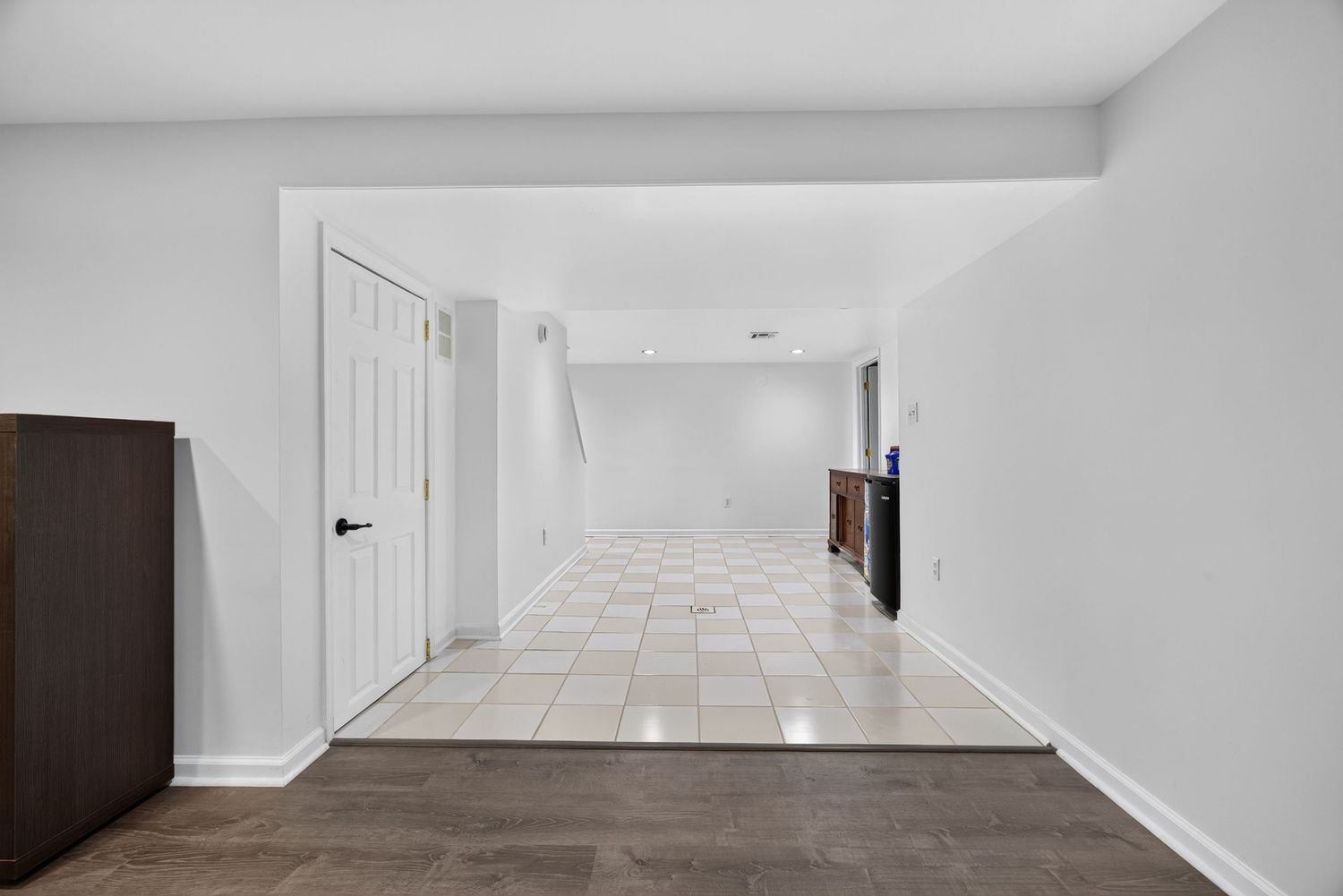 Bright open hallway with white walls, light tile flooring, and a white door leading to additional living space.