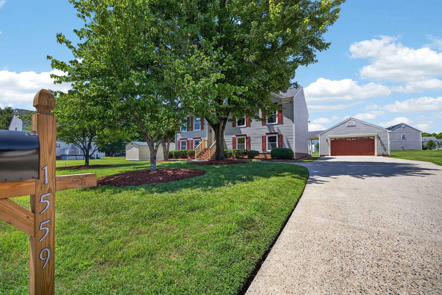 Two-story brick home at 1559 with a large tree, manicured lawn, and attached garage on a sunny day.