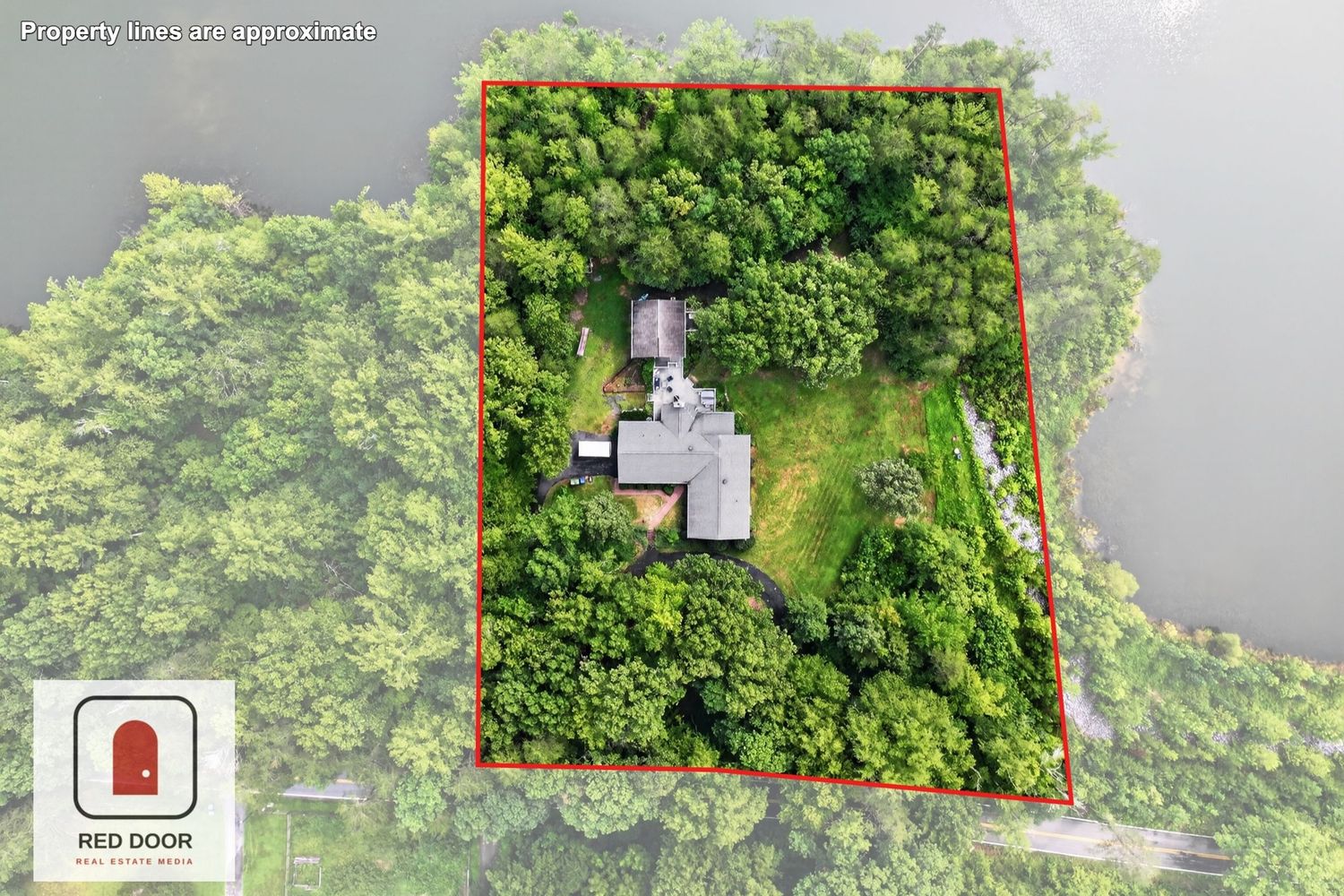 Aerial view of a secluded wooded property with a house surrounded by lush green trees, outlined by a red boundary marker.