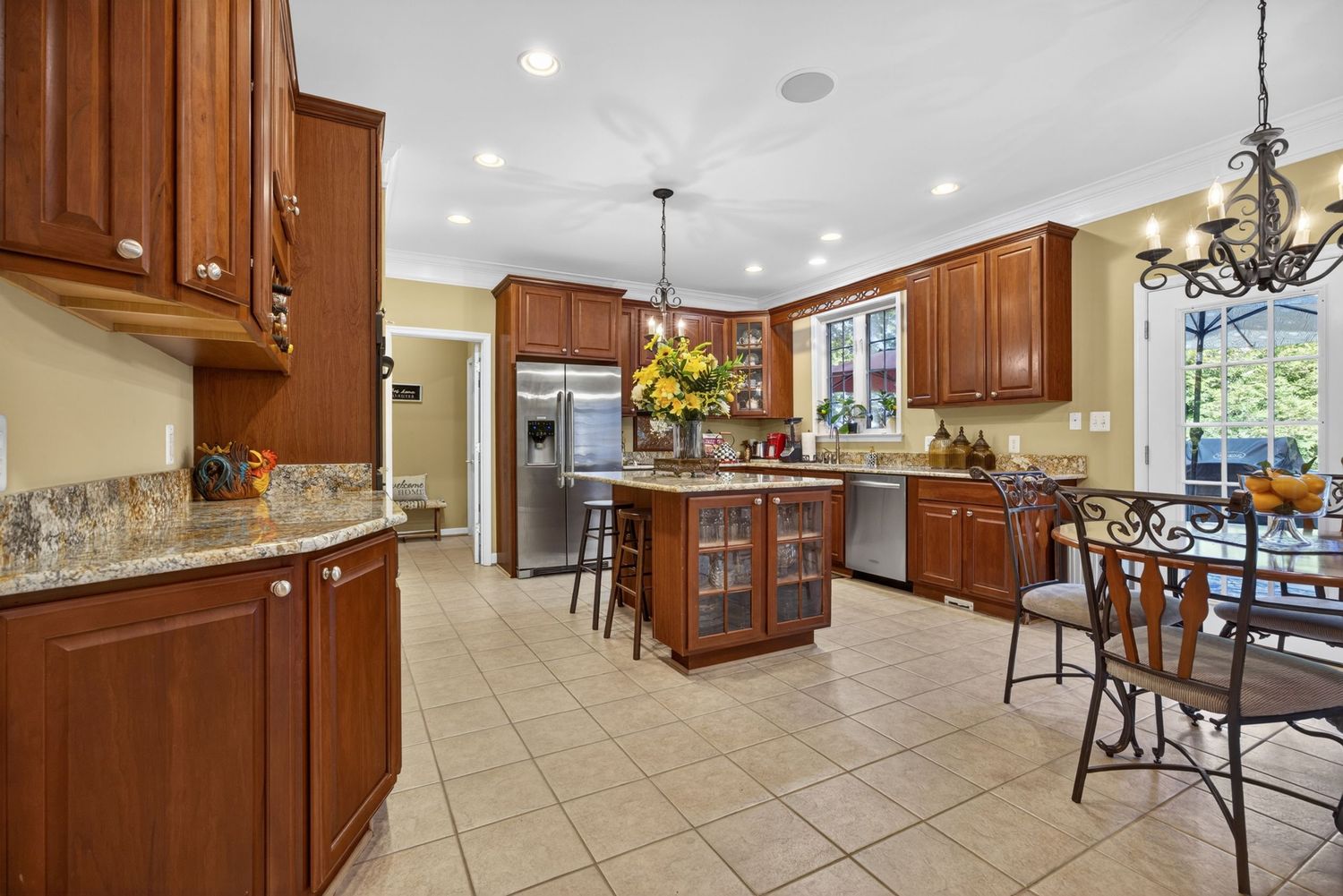 Spacious kitchen with cherry wood cabinets, granite countertops, stainless steel appliances, center island, and tile flooring.