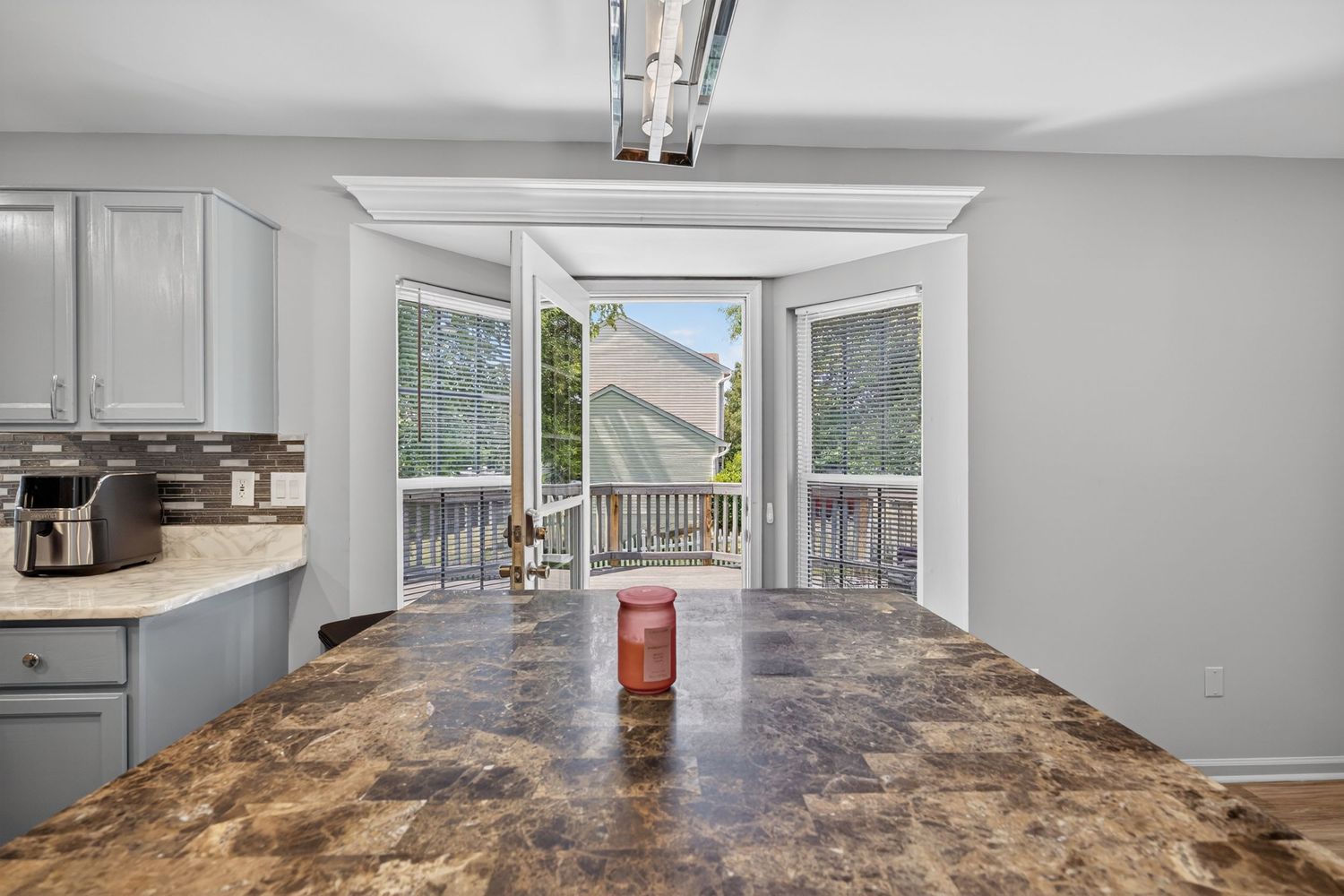 Kitchen dining area with granite floors, gray cabinets, and glass doors opening to a deck with outdoor views.