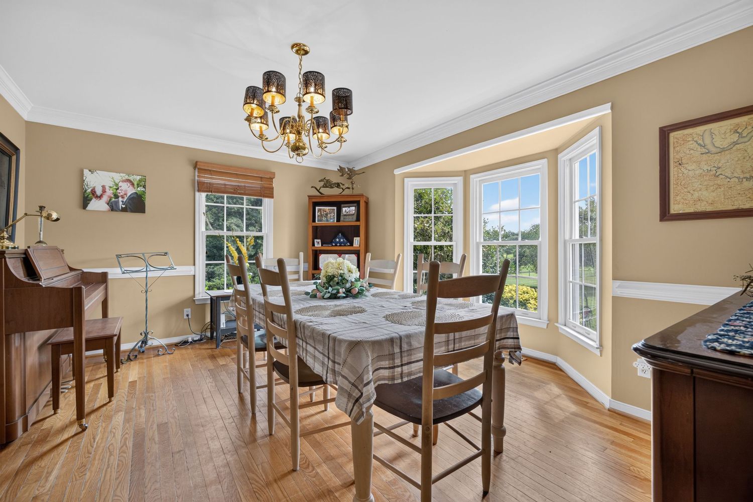Bright dining room with hardwood floors, chandelier, wooden table set, and large windows filling the space with natural light.