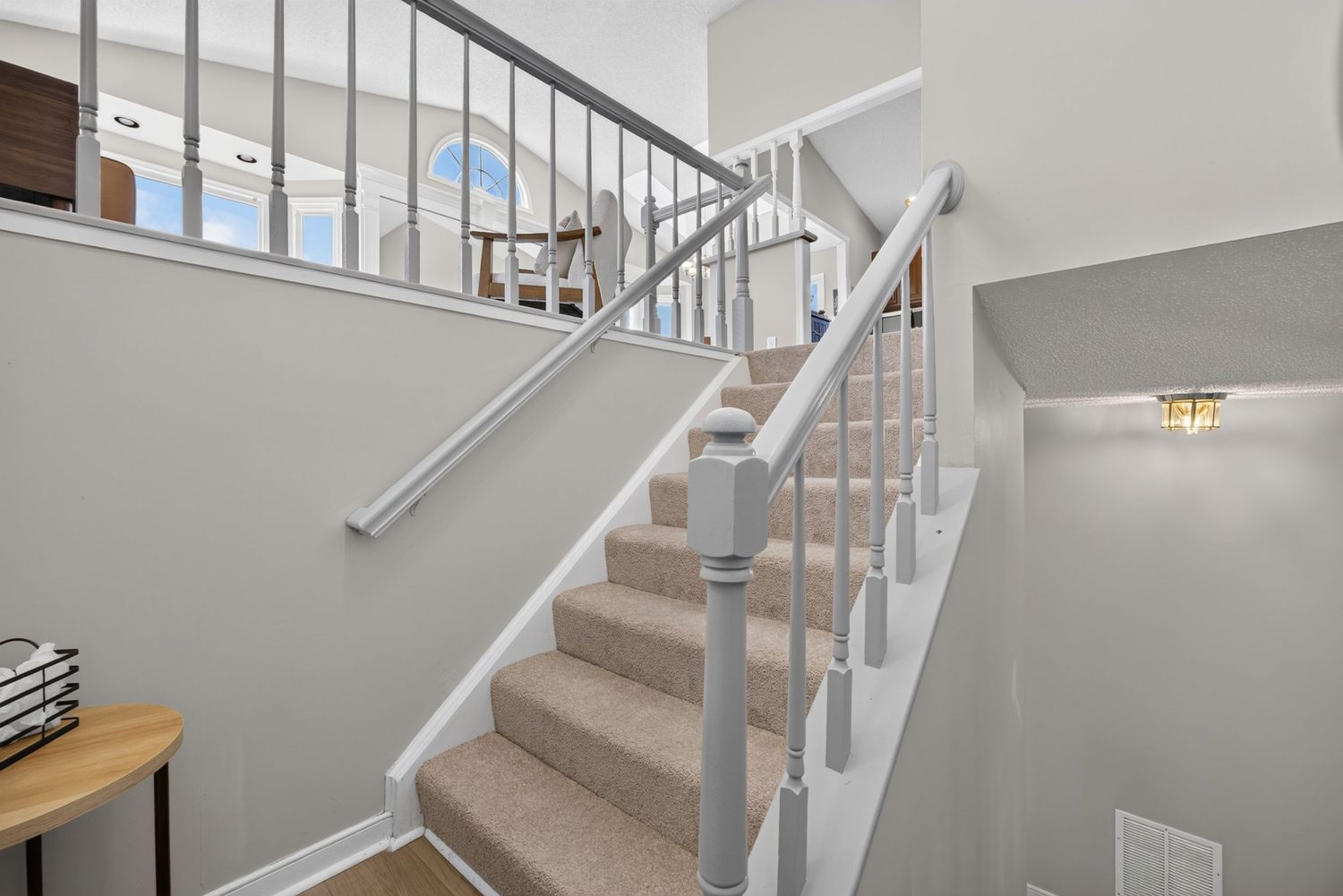 Bright interior staircase with white risers, gray carpet treads, and modern metal balusters leading to an upper level.