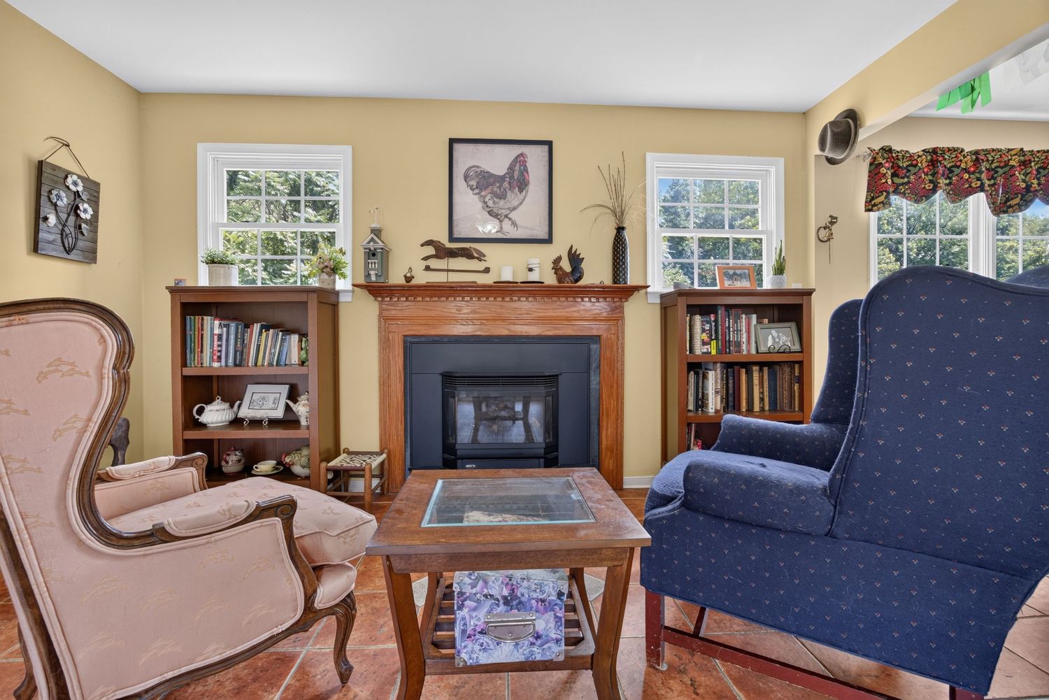 Cozy living room with fireplace, built-in bookshelves, wingback chairs, and warm wood flooring in a traditional home.