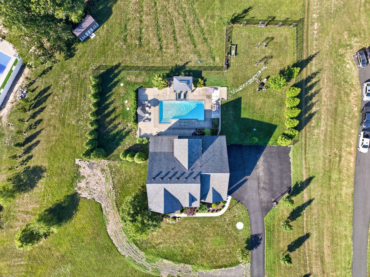Aerial view of a large suburban home with a backyard pool, surrounded by lush green lawns and landscaped grounds.