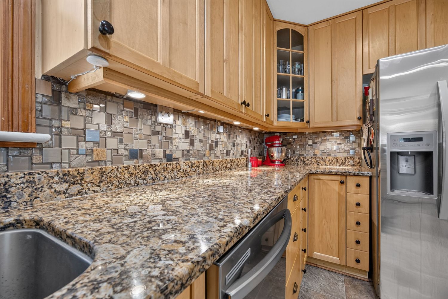Modern kitchen with granite countertops, mosaic tile backsplash, oak cabinets, and stainless steel appliances.