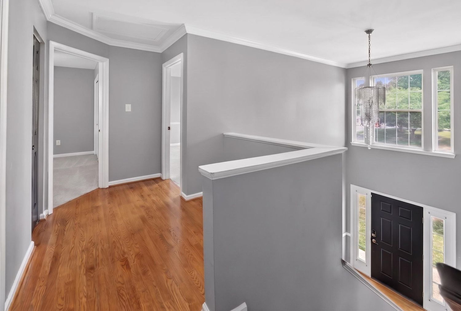 Bright open interior hallway with hardwood floors, gray walls, and pendant light in modern home.
