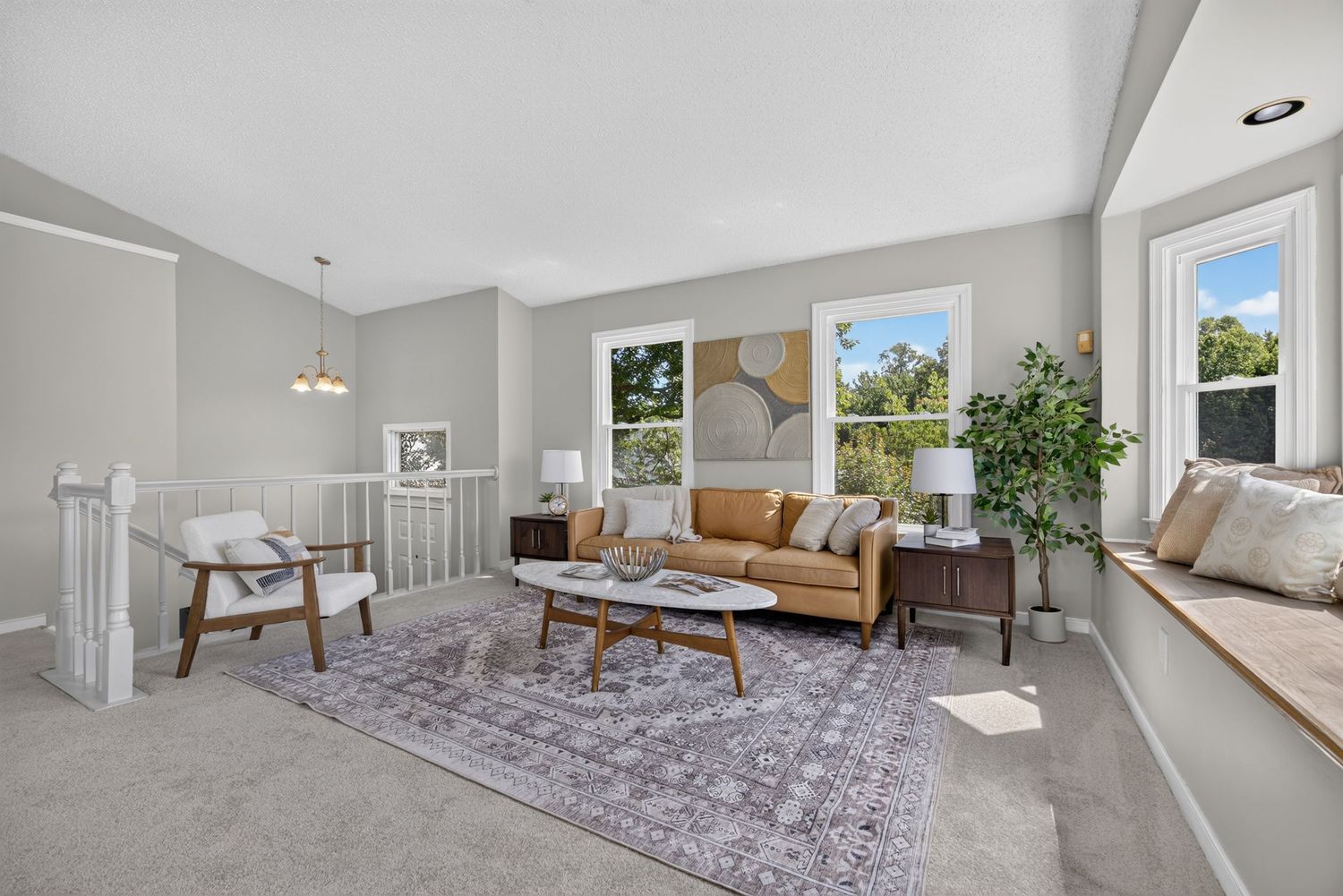 Bright living room with gray walls, carpet, mid-century sofa, coffee table, area rug, and large windows with natural light.