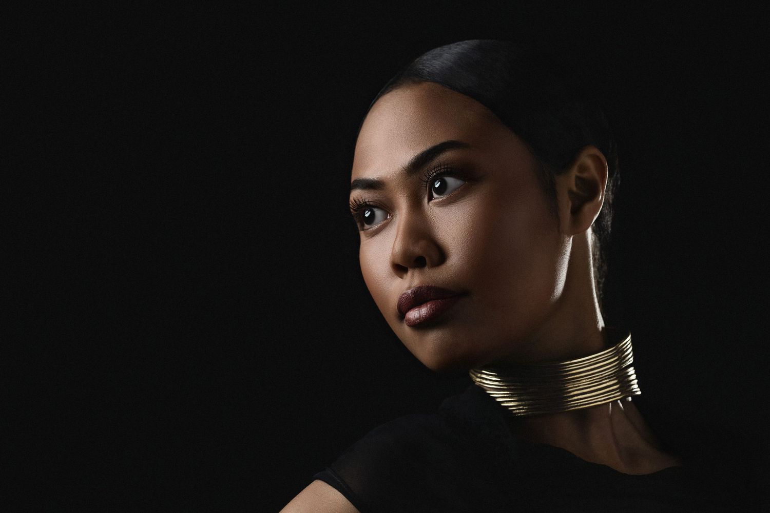 Artistic portraits featuring gold neck accessories and dramatic side lighting against dark background.