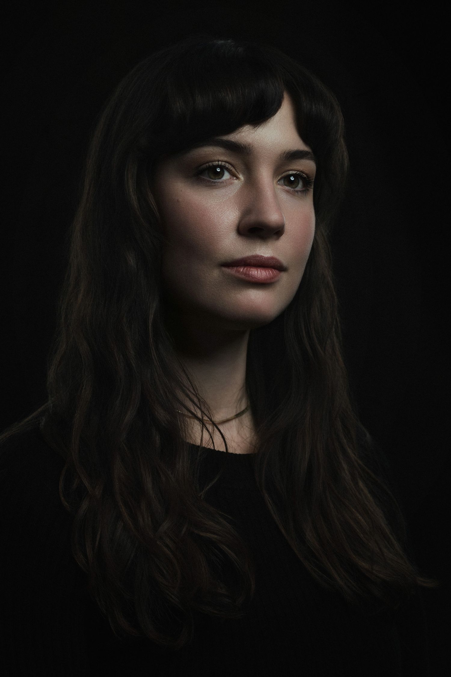 Artistic portrait series with wavy hair and dramatic shadows against dark background.