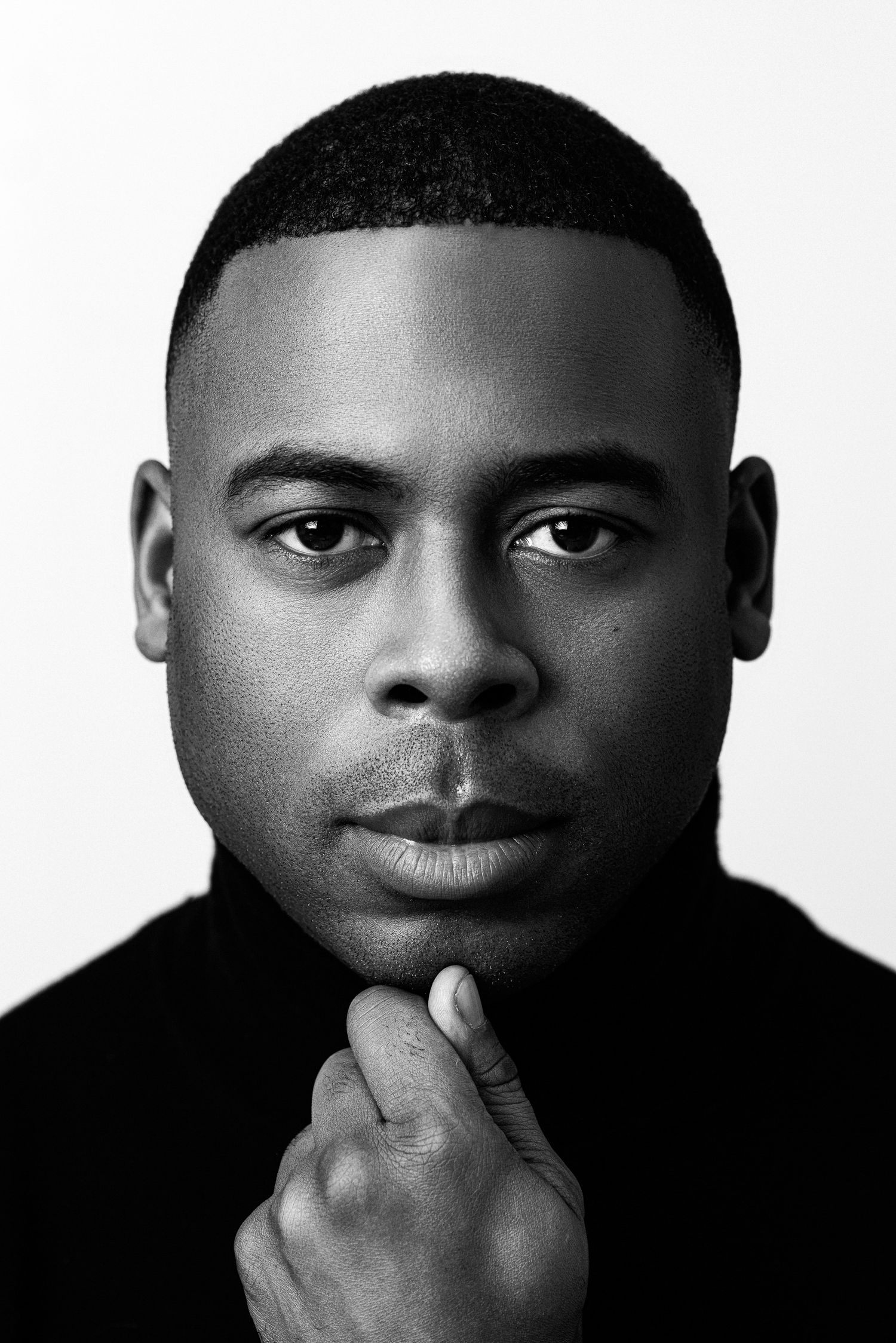 Close-up black and white portrait with hand touching chin.