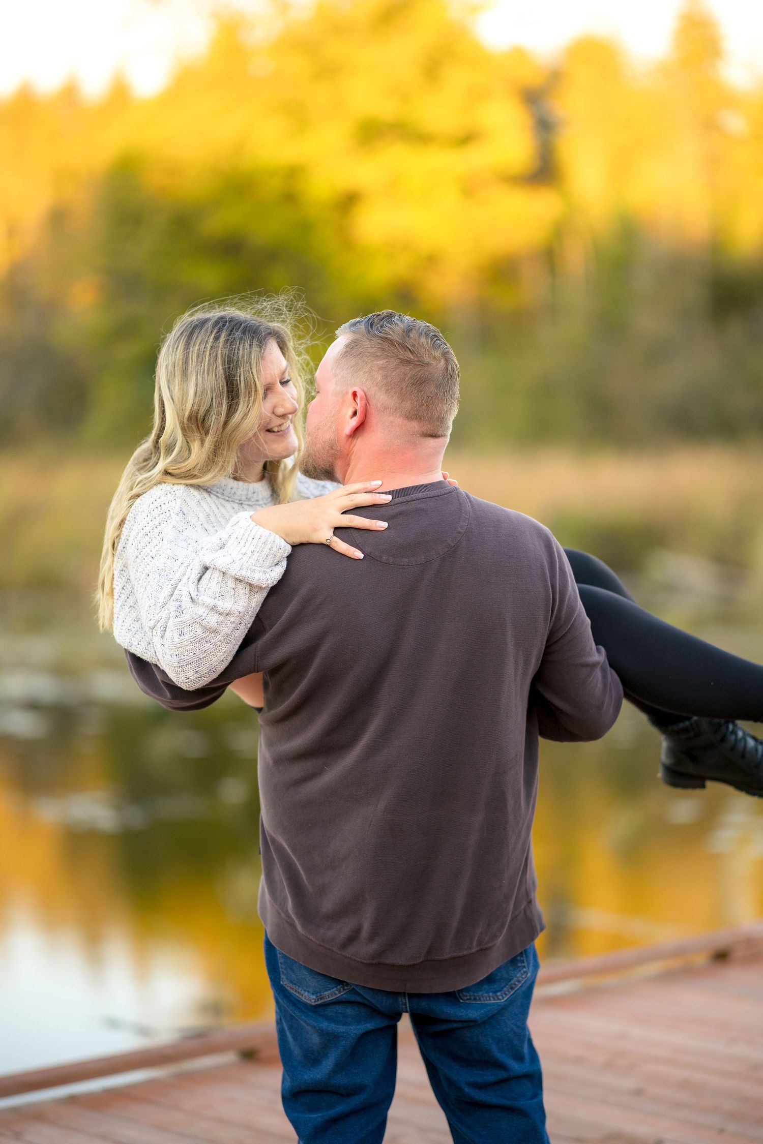 Romantic couple embracing on wooden bridge during golden hour sunset. Ottawa Portrait Photographer