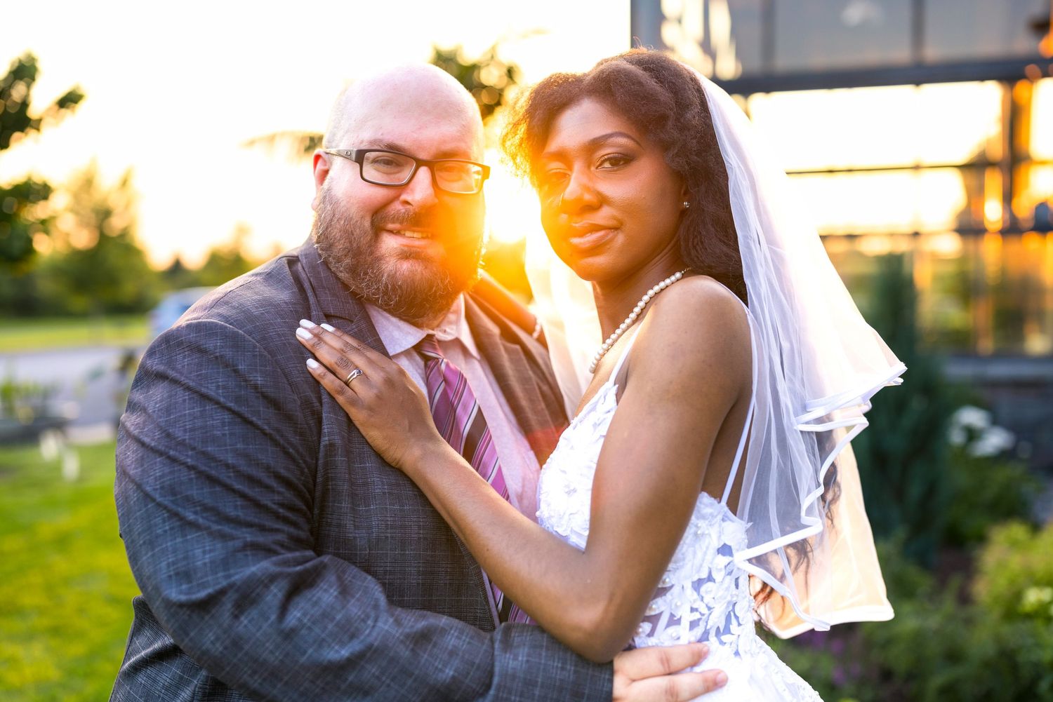 Newlywed couple poses together in a romantic sunset portrait with sun flare behind them outdoors. Tim Gowling Ottawa Wedding Photography