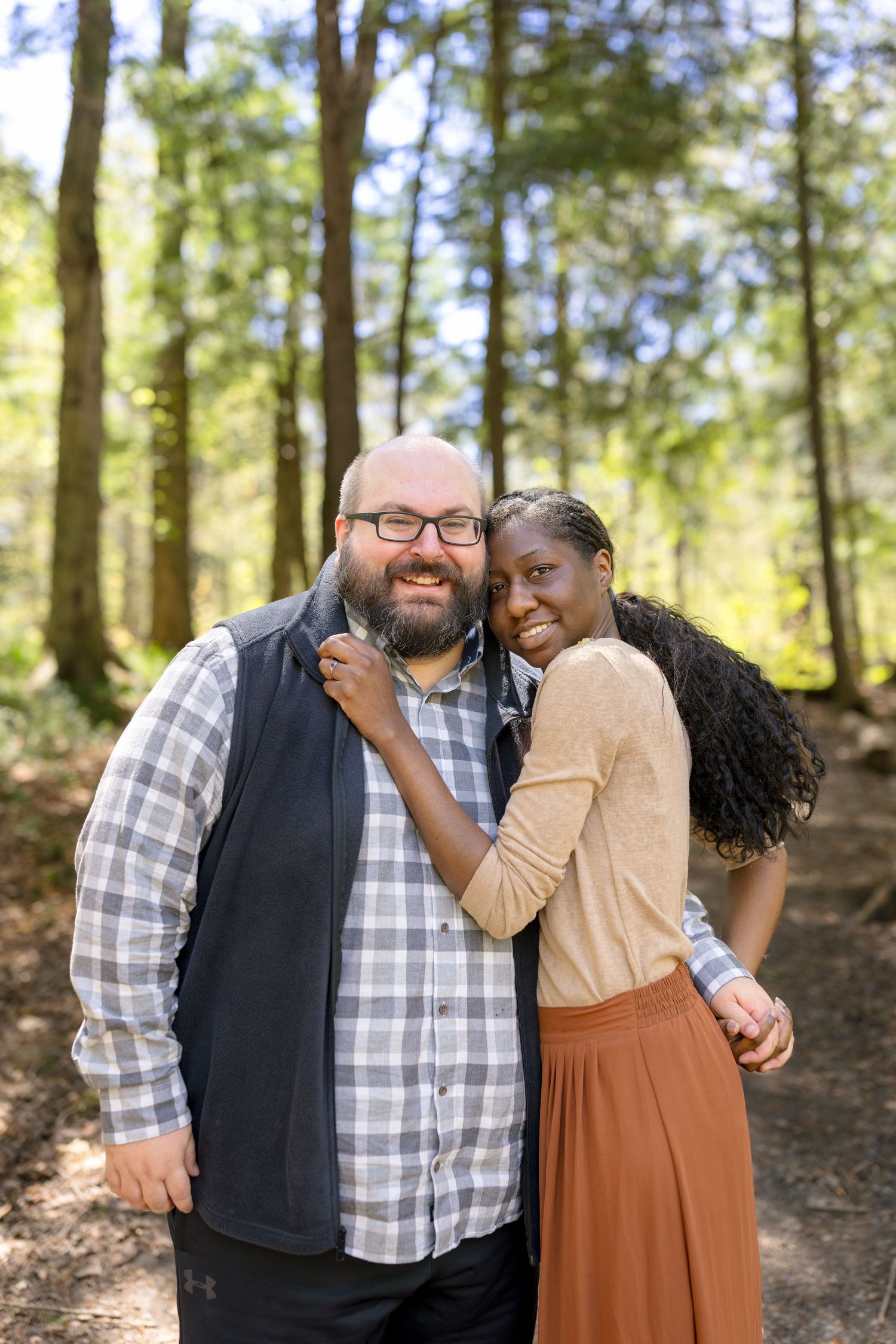 Couple enjoying playful moments together in a sunny woodland setting. Ottawa Wedding Photographer