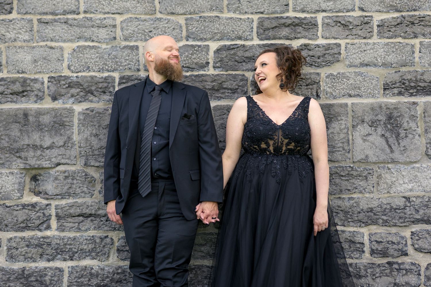 A couple shares a romantic moment standing against a stone wall at St Raphael's Catholic Church Ruins with Ottawa Wedding Photographer