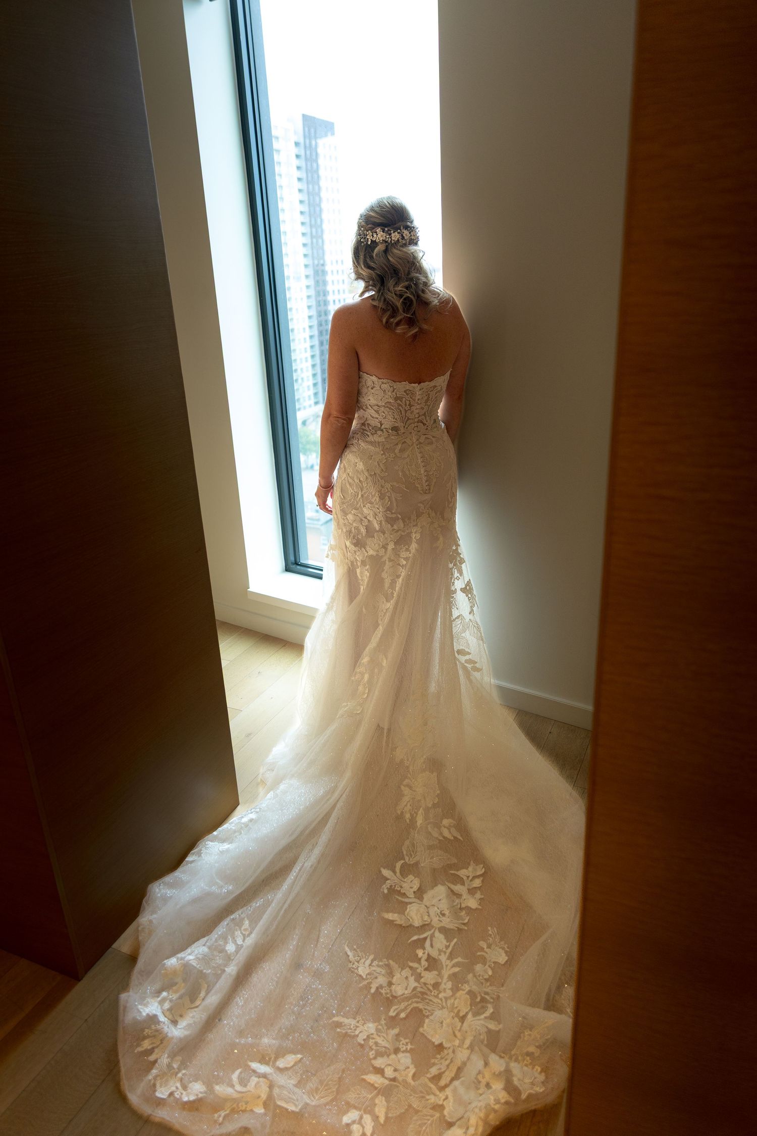 A wedding dress with intricate lace details and flowing train in natural window light. Ottawa wedding photographer